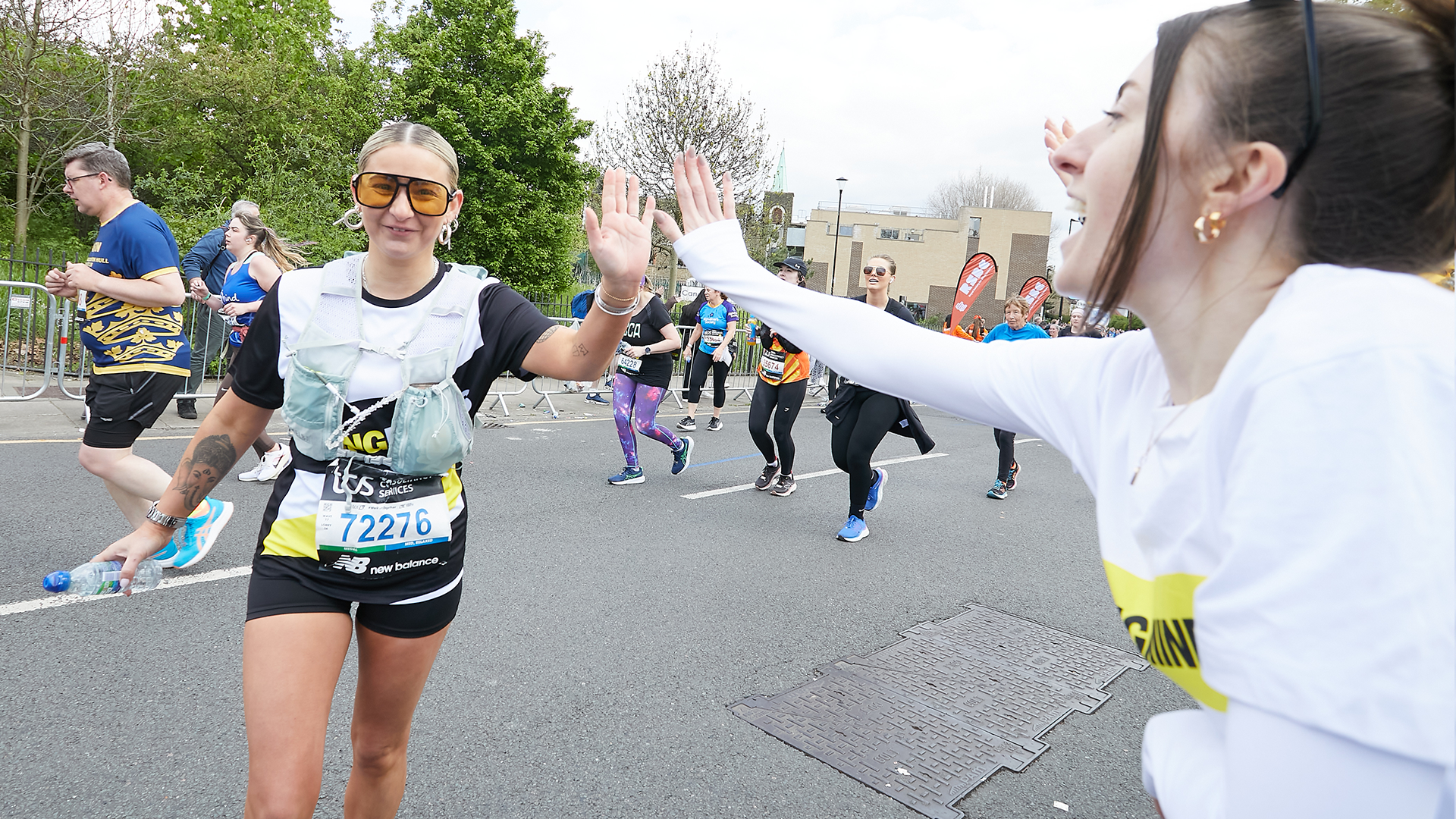 A YoungMinds marathon runner being supported by YoungMinds staff on the side line with a high five.