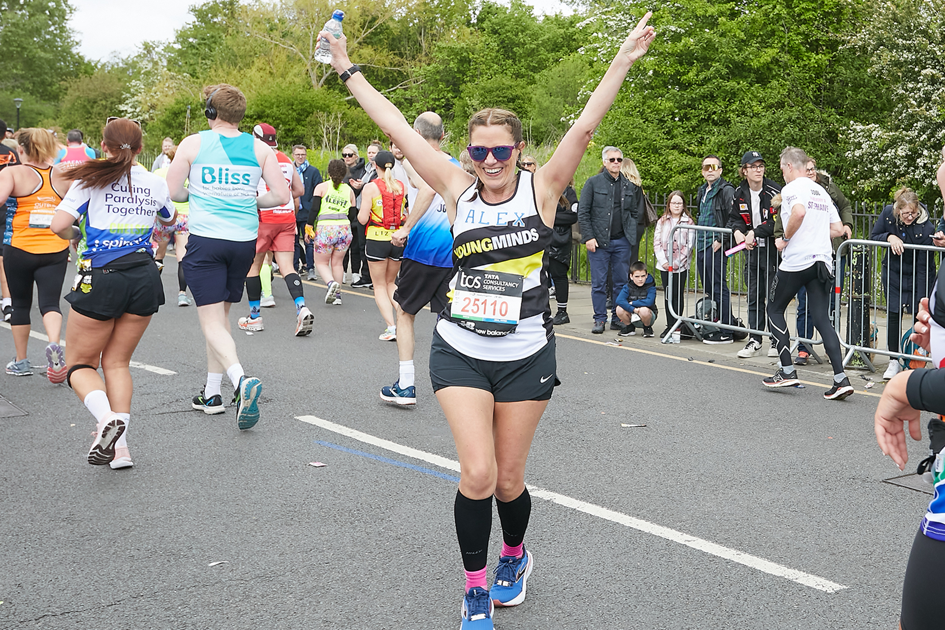 A YoungMinds marathon runner running with their hands in the air and smiling.