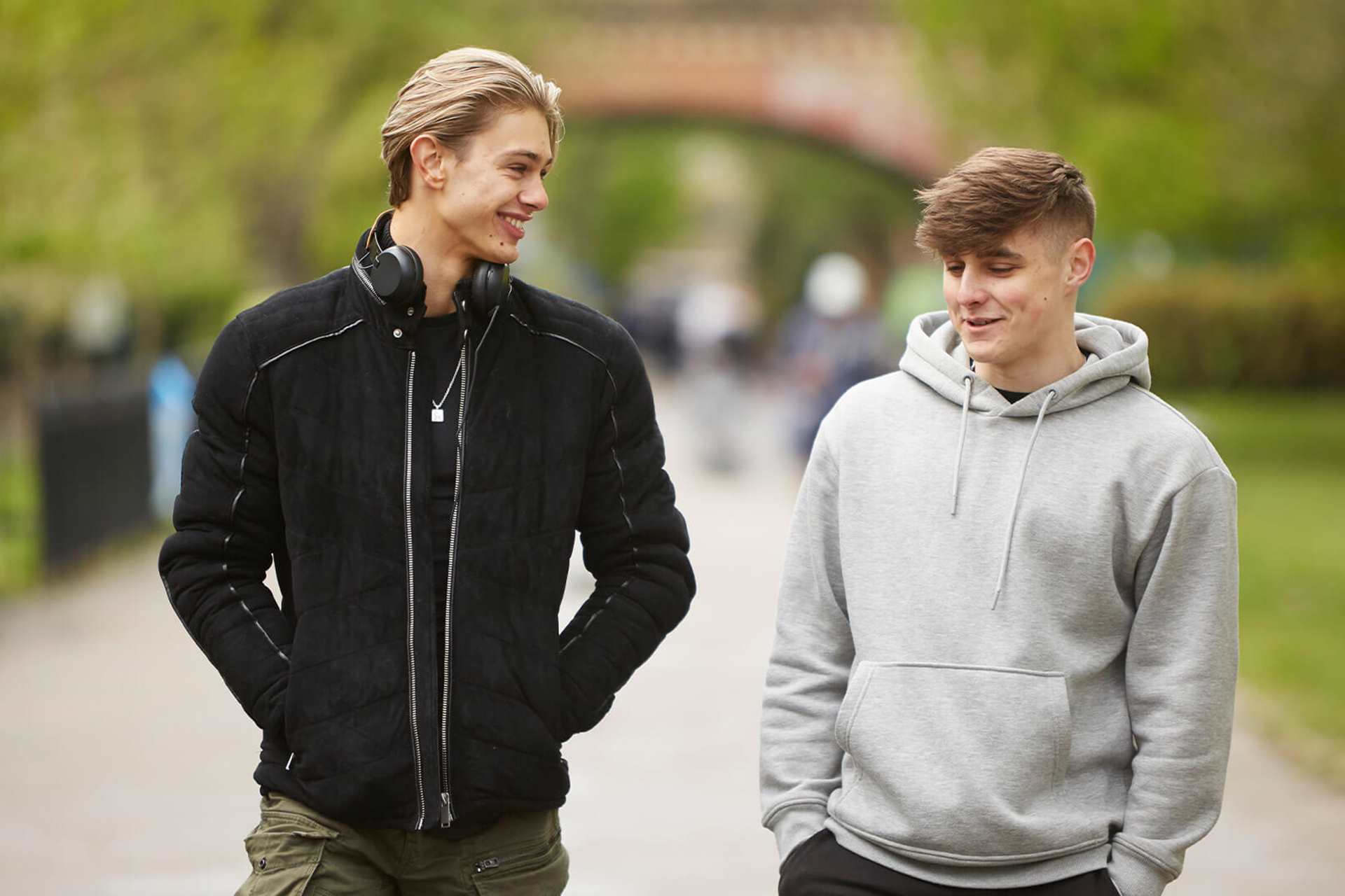 two-young-man-wearing-grey-hoodie-and-black-jacket-walking-and-laughing-on-a-street