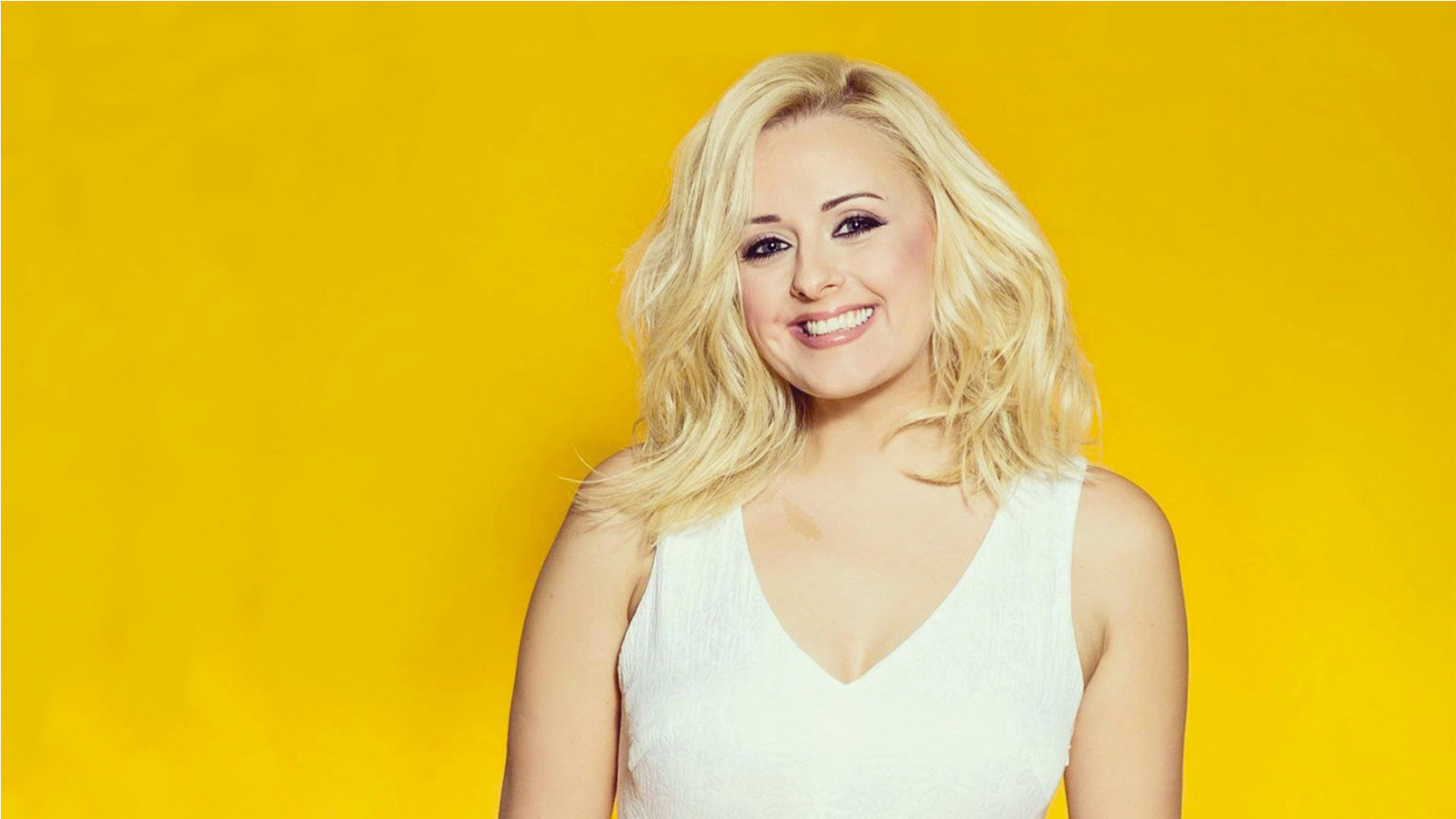 Katie Thistleton smiling and wearing a cream dress against a yellow background.