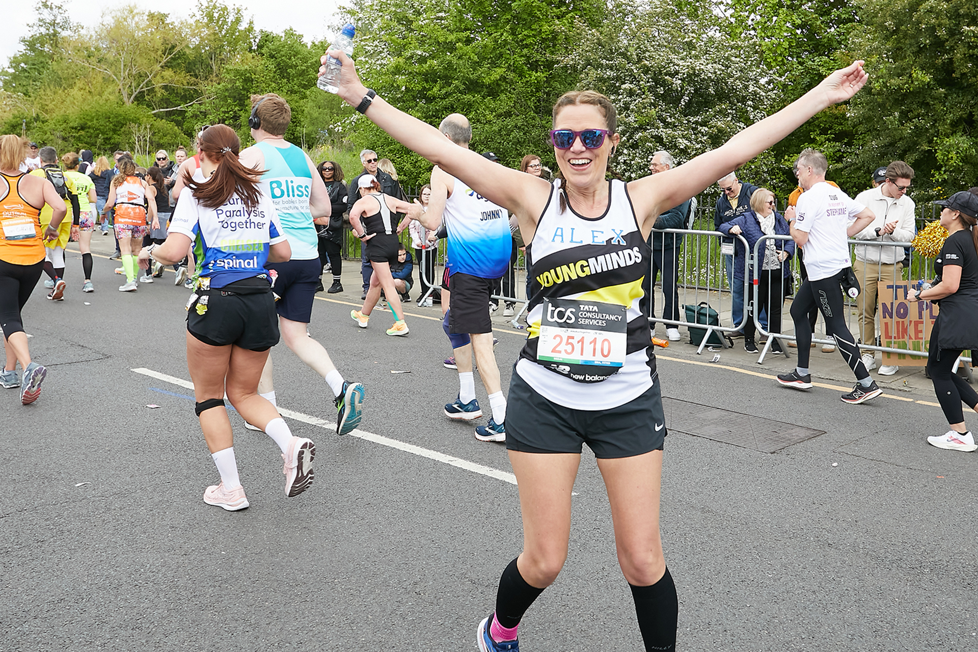 A YoungMinds marathon runner running with their hands in the air and smiling.
