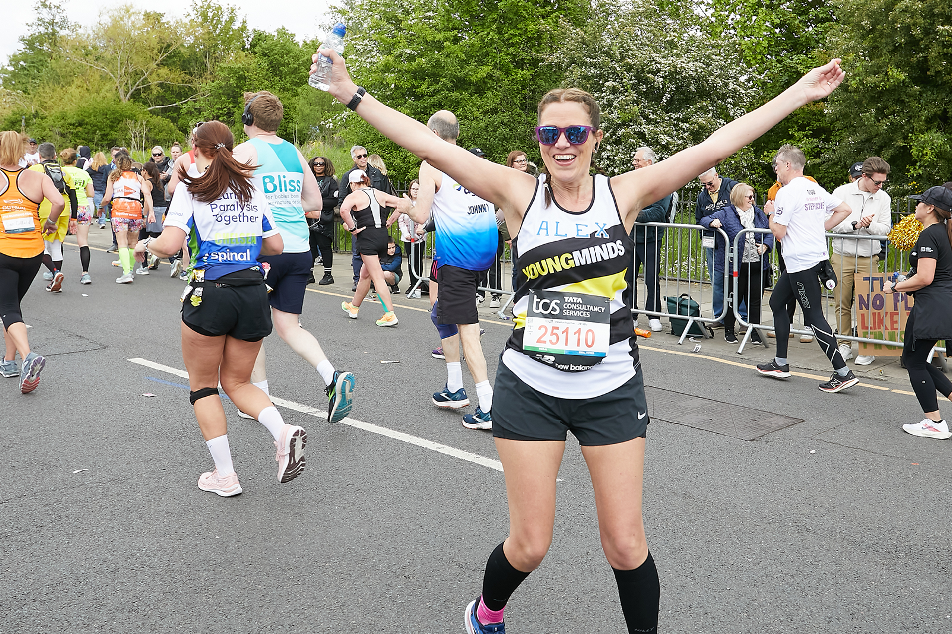 A YoungMinds marathon runner running with their hands in the air and smiling.