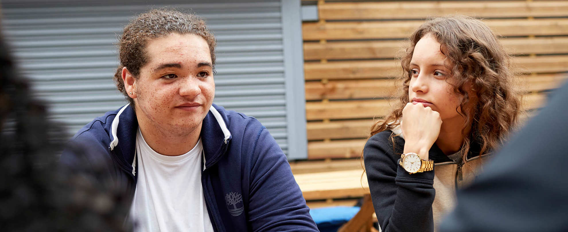 Two young people sitting together at a picnic bench with their friends.
