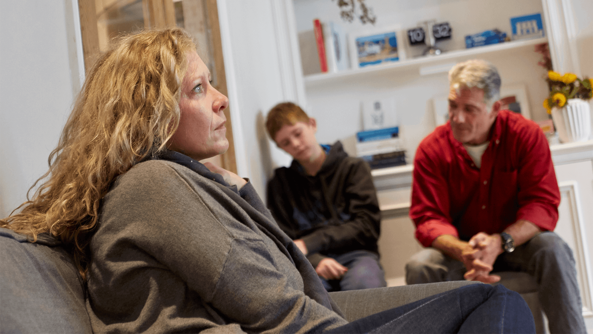 A family sitting in a room looking serious and sad