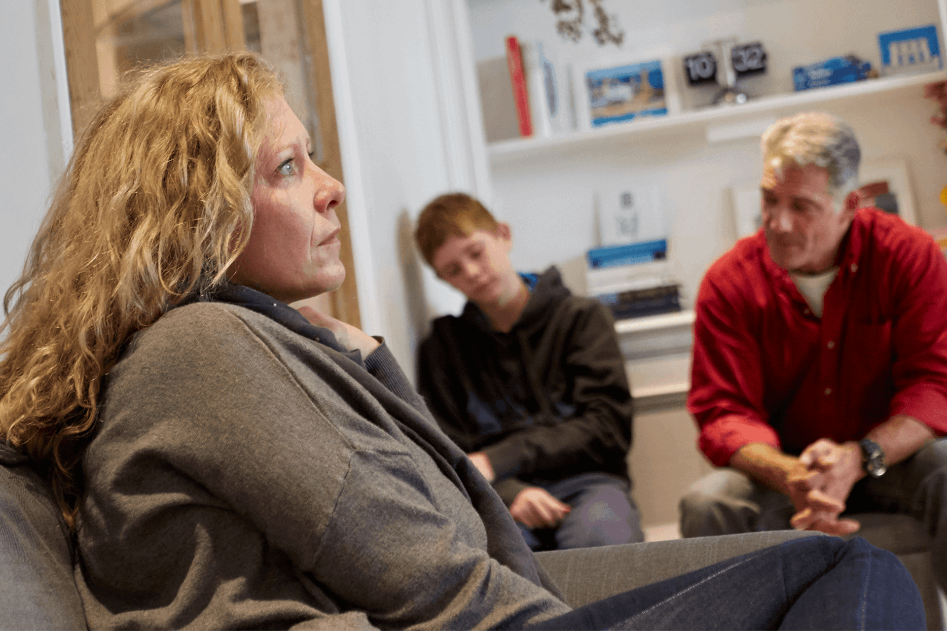 A family sitting in a room looking serious and sad