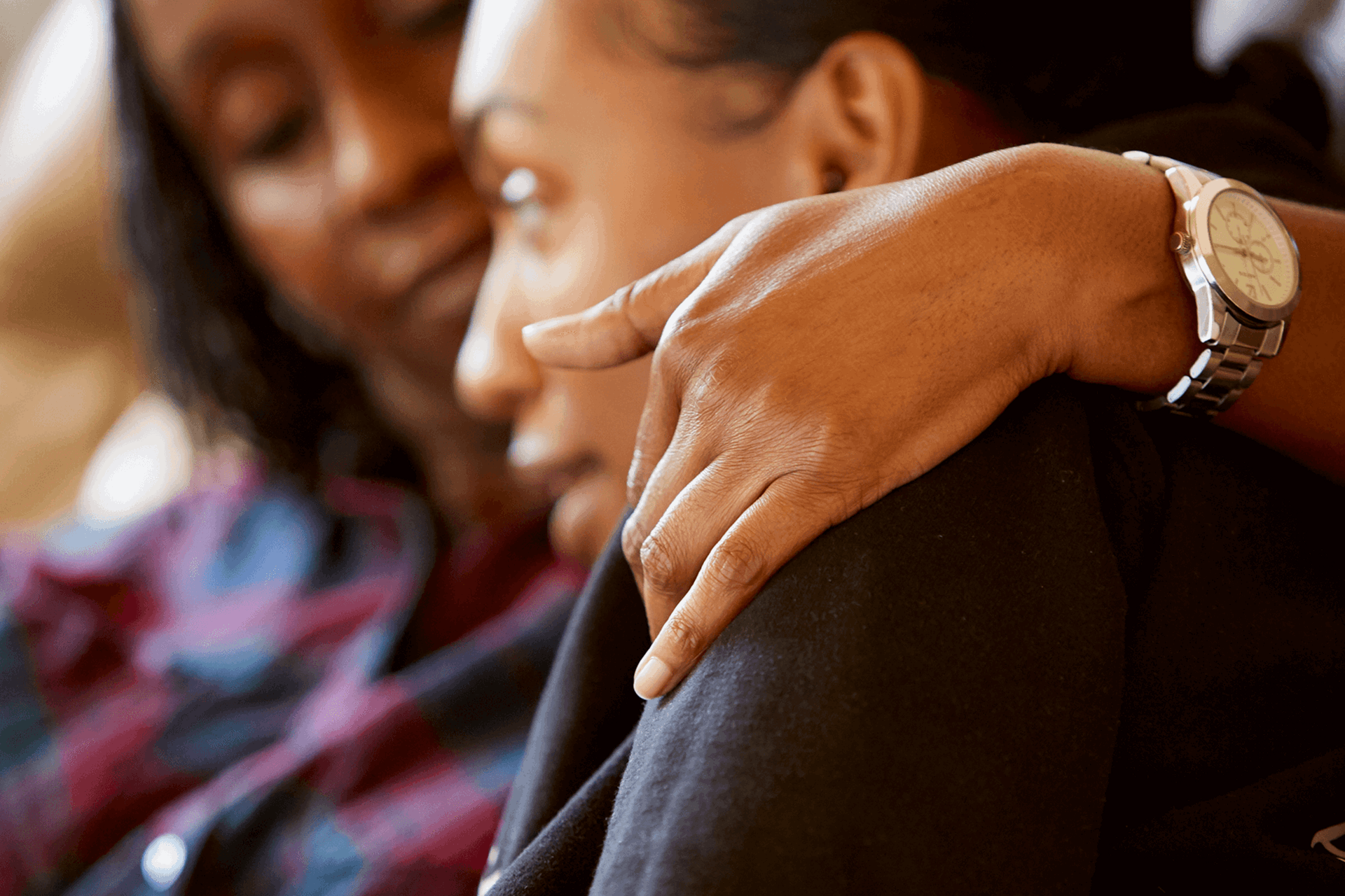 A mother comforts her daughter at their home.