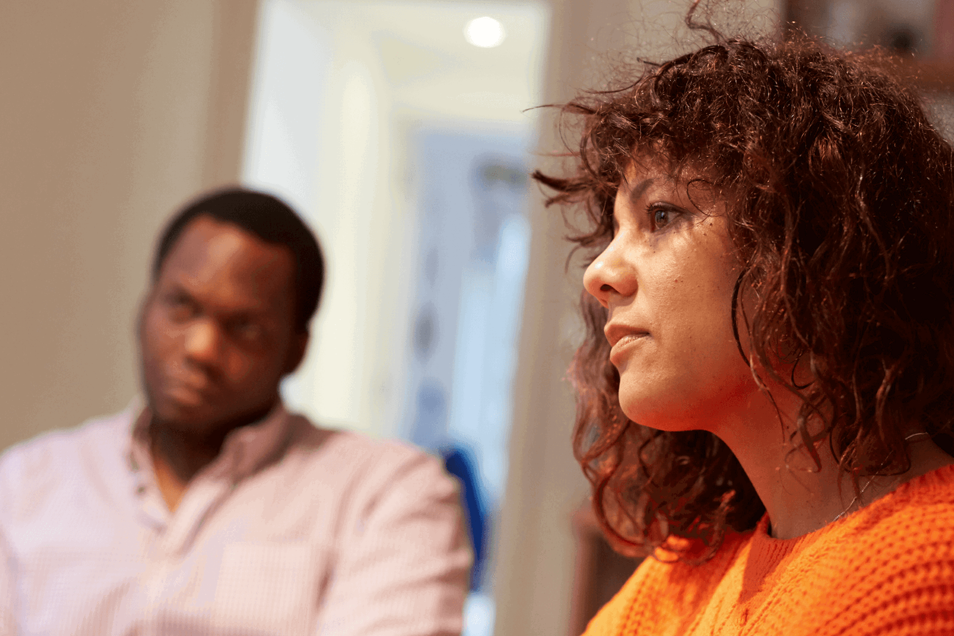 A man and woman sit in a room listening to something 