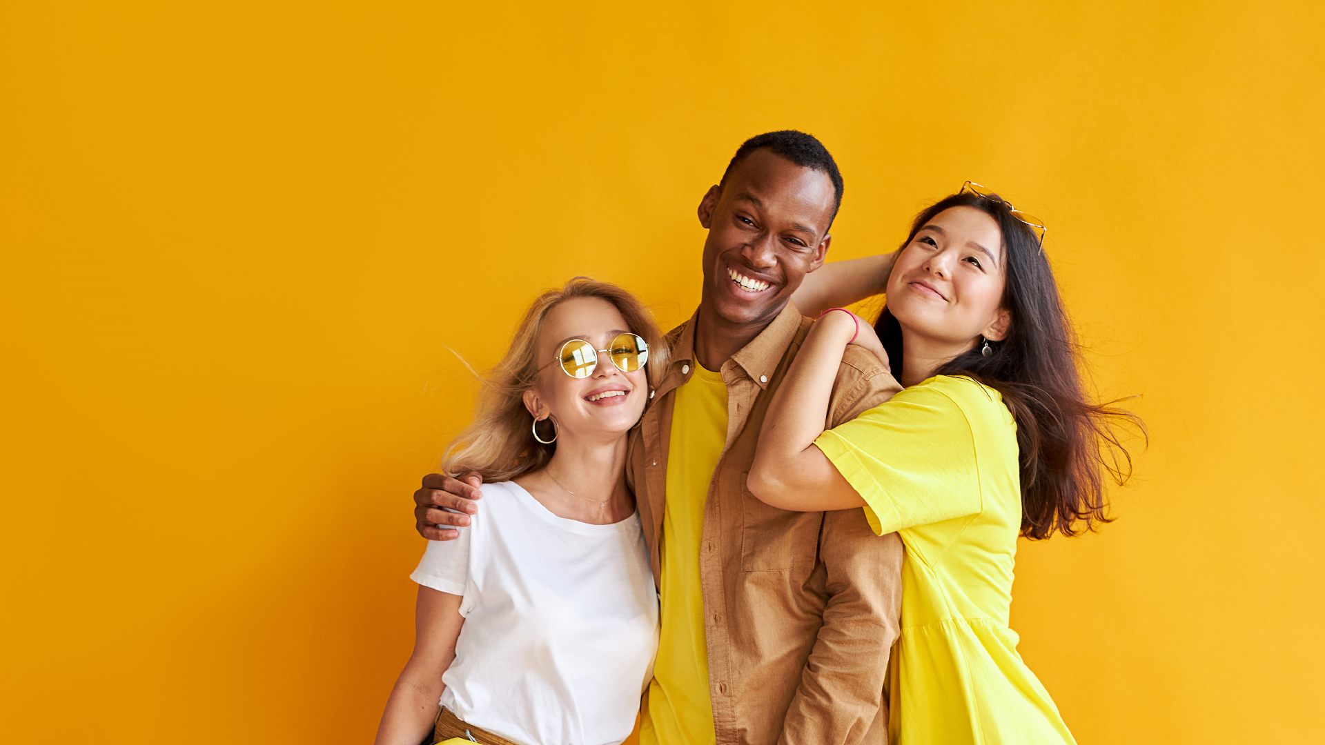Three people wearing yellow with their arms around each other.