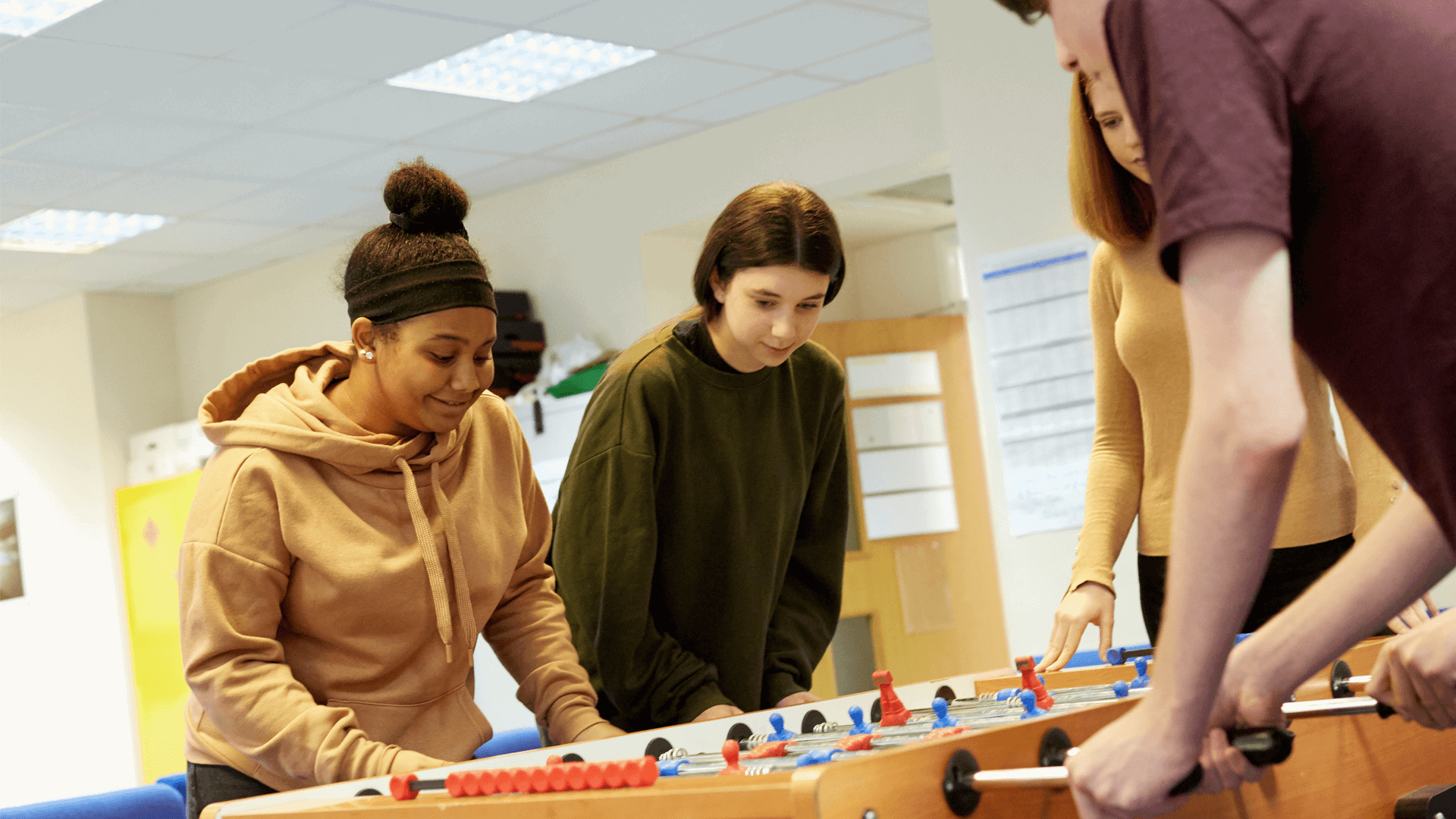 four-young-people-serious-in-playing-table football in campus