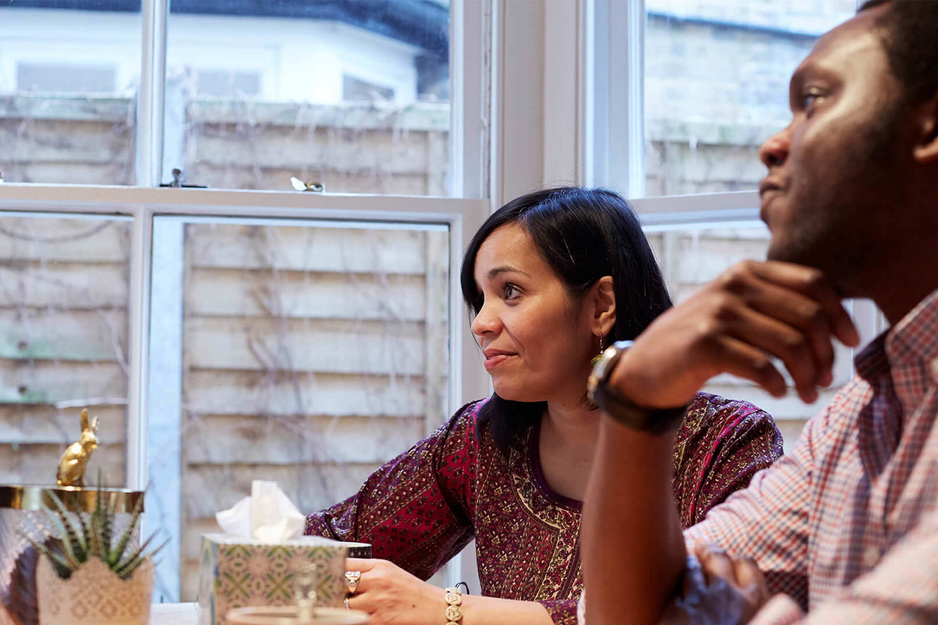 A man and woman sit at a table deep in conversation with others out of the shot 