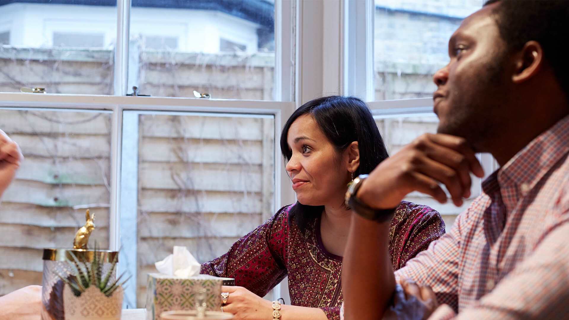 A man and woman sit at a table deep in conversation with others out of the shot 