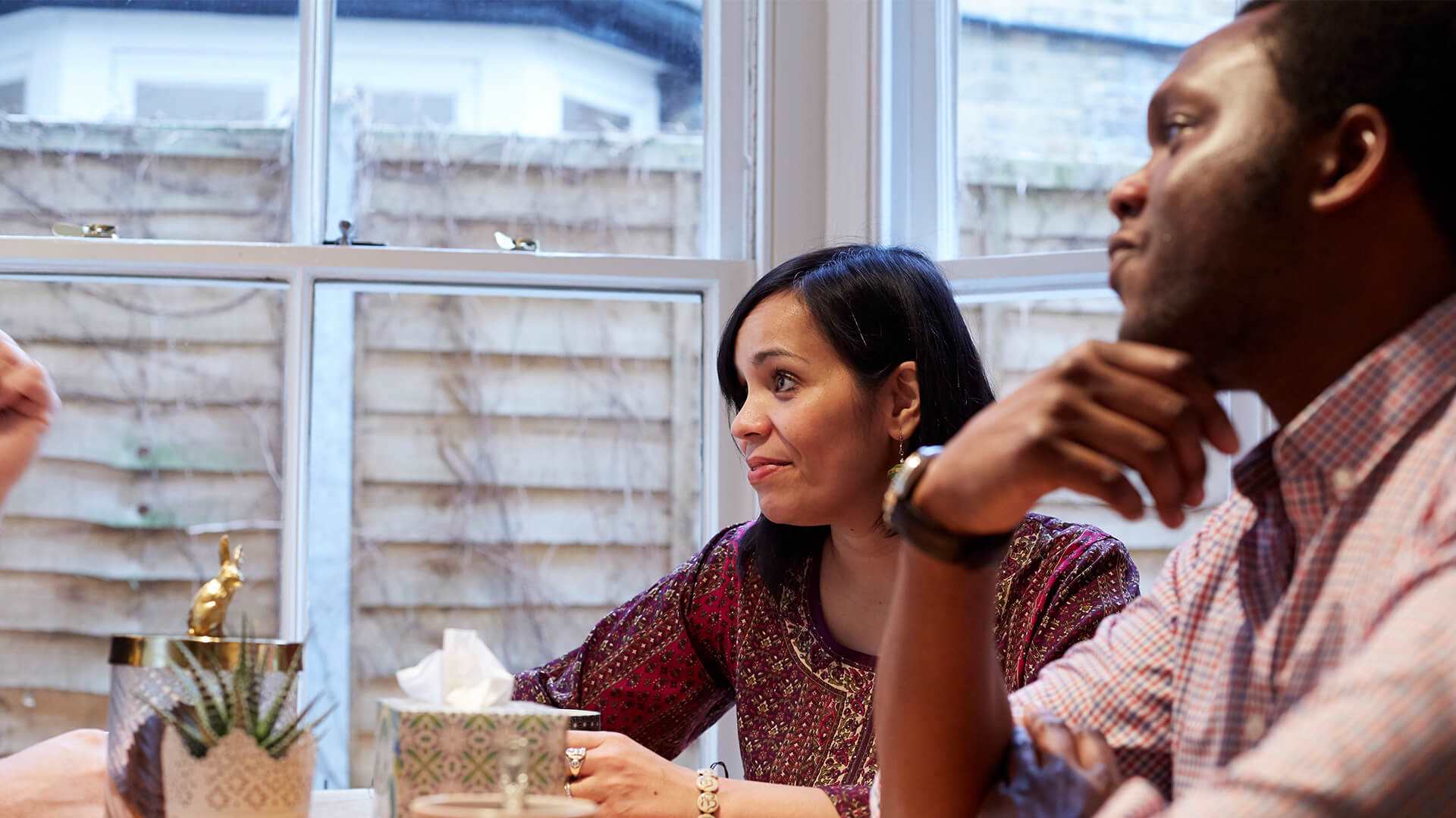 A man and woman sit at a table deep in conversation with others out of the shot