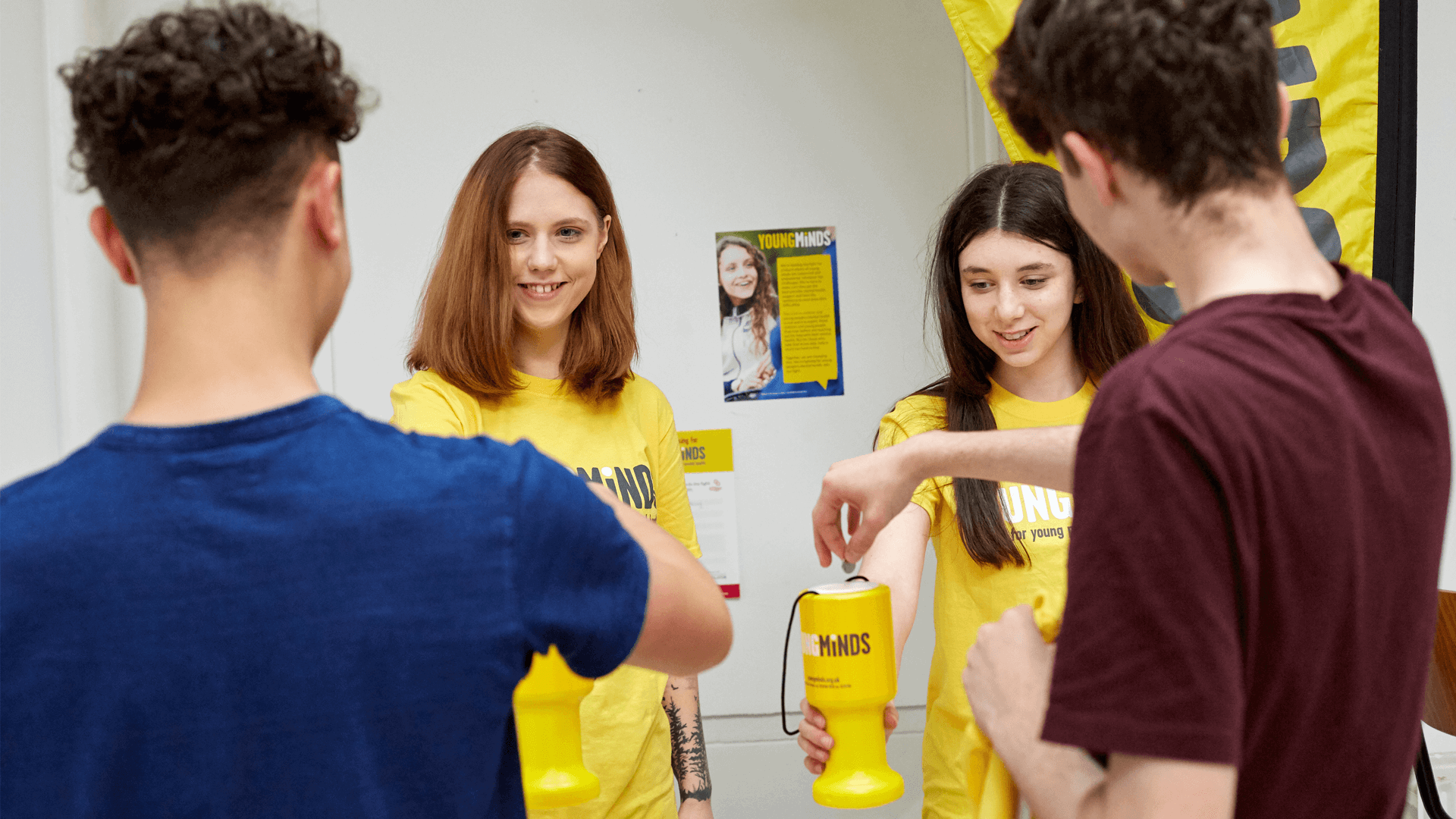 YoungMinds volunteers are smiling while handing out coin banks in a fundraising event