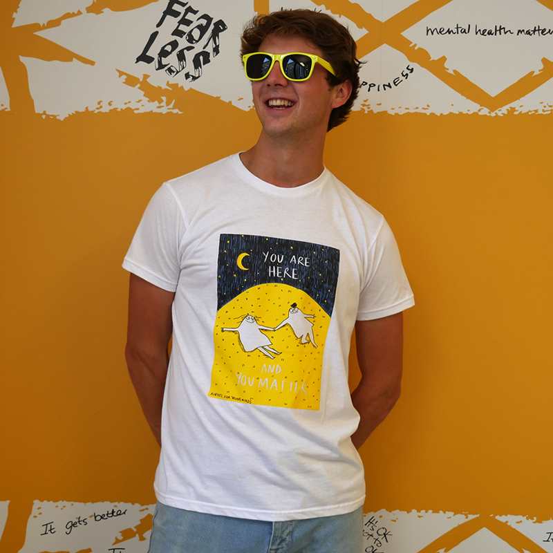 A man smiling wearing yellow sunglasses and our Rubyetc bespoke 'You are here and you matter' graphic #HelloYellow T-shirt