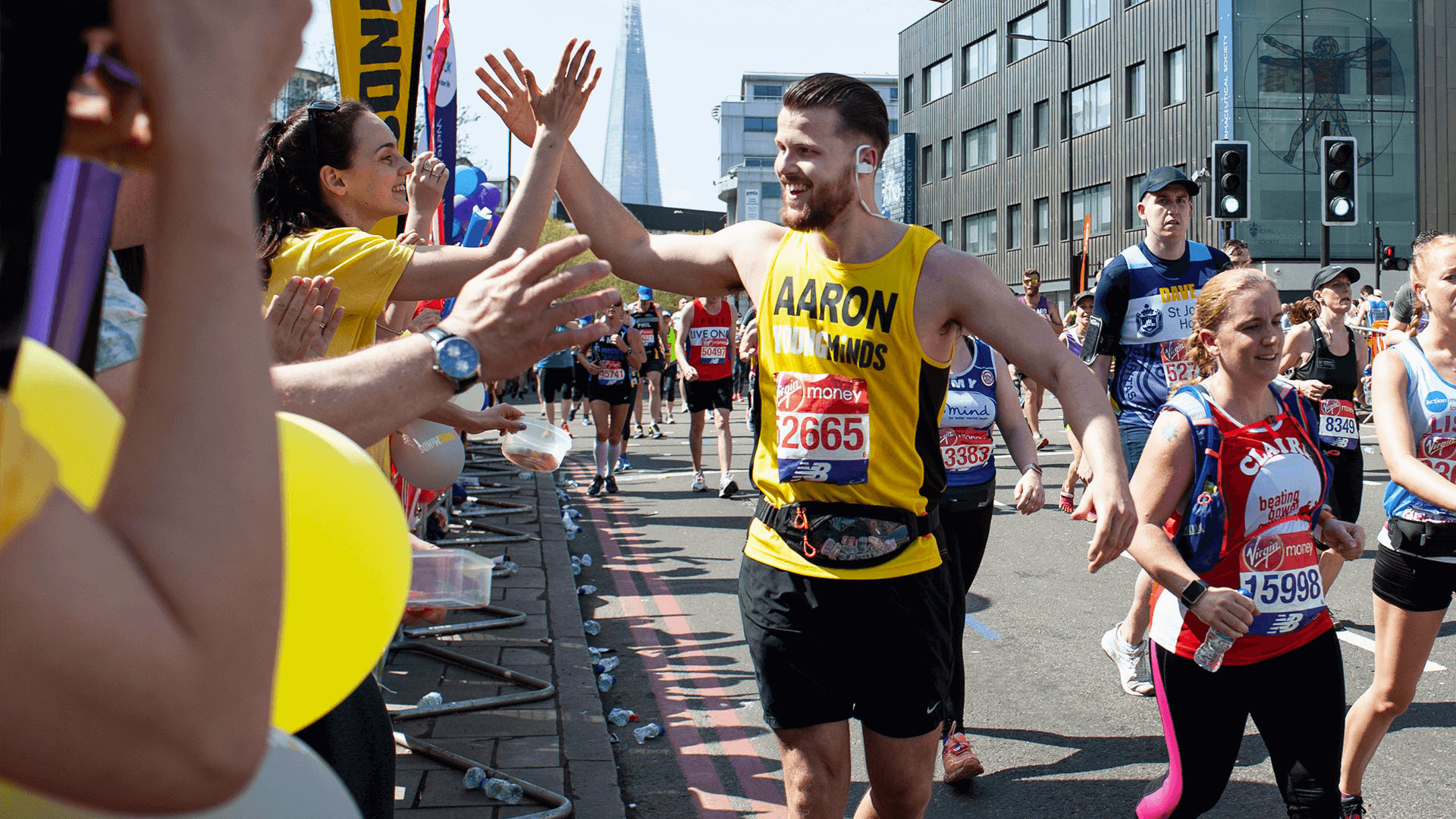 Runner gives a high five to a YoungMinds cheerer in the crowd during a marathon
