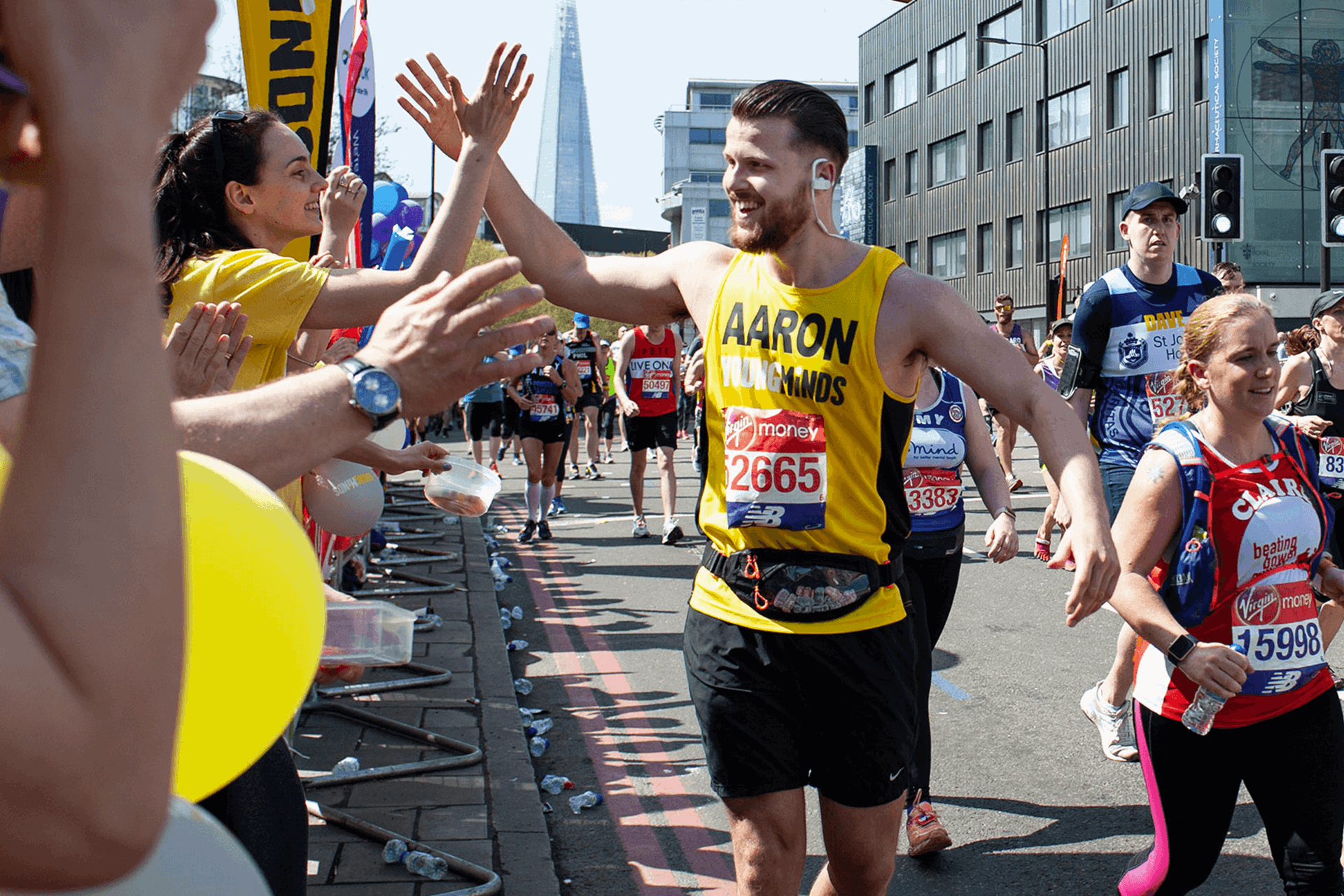 Runner gives a high five to a YoungMinds cheerer in the crowd during a marathon
