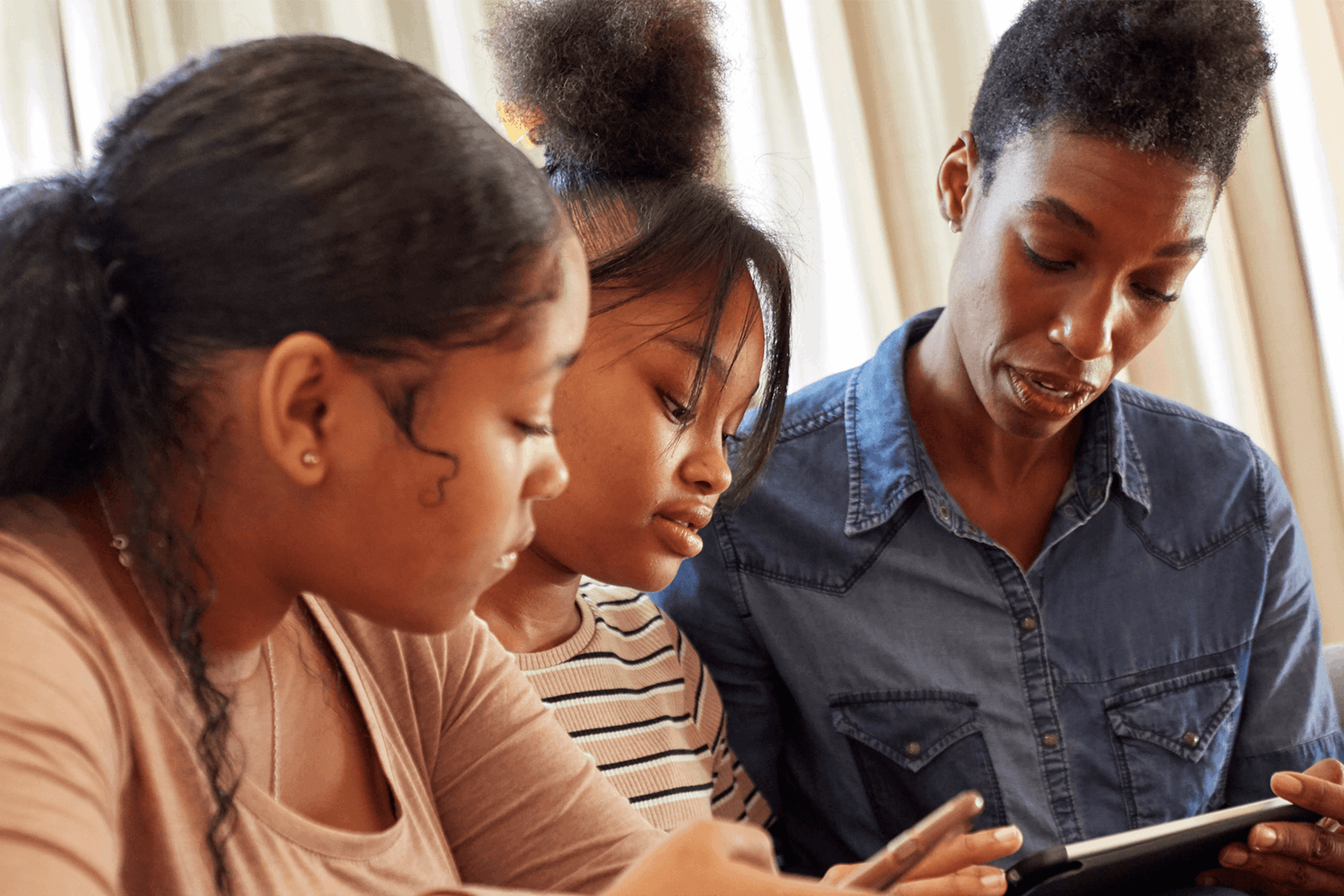 Mother and daughters using mobile devices together