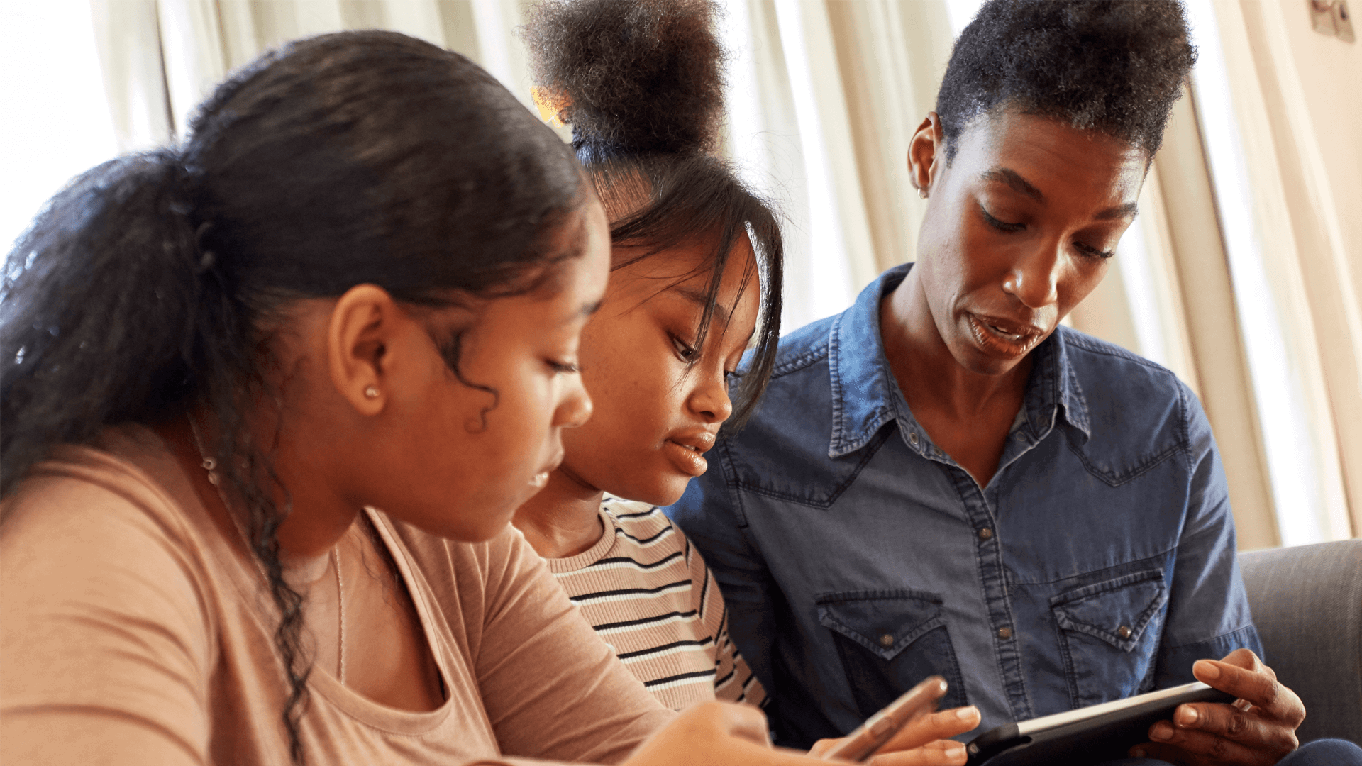 Mother and daughters using mobile devices together 