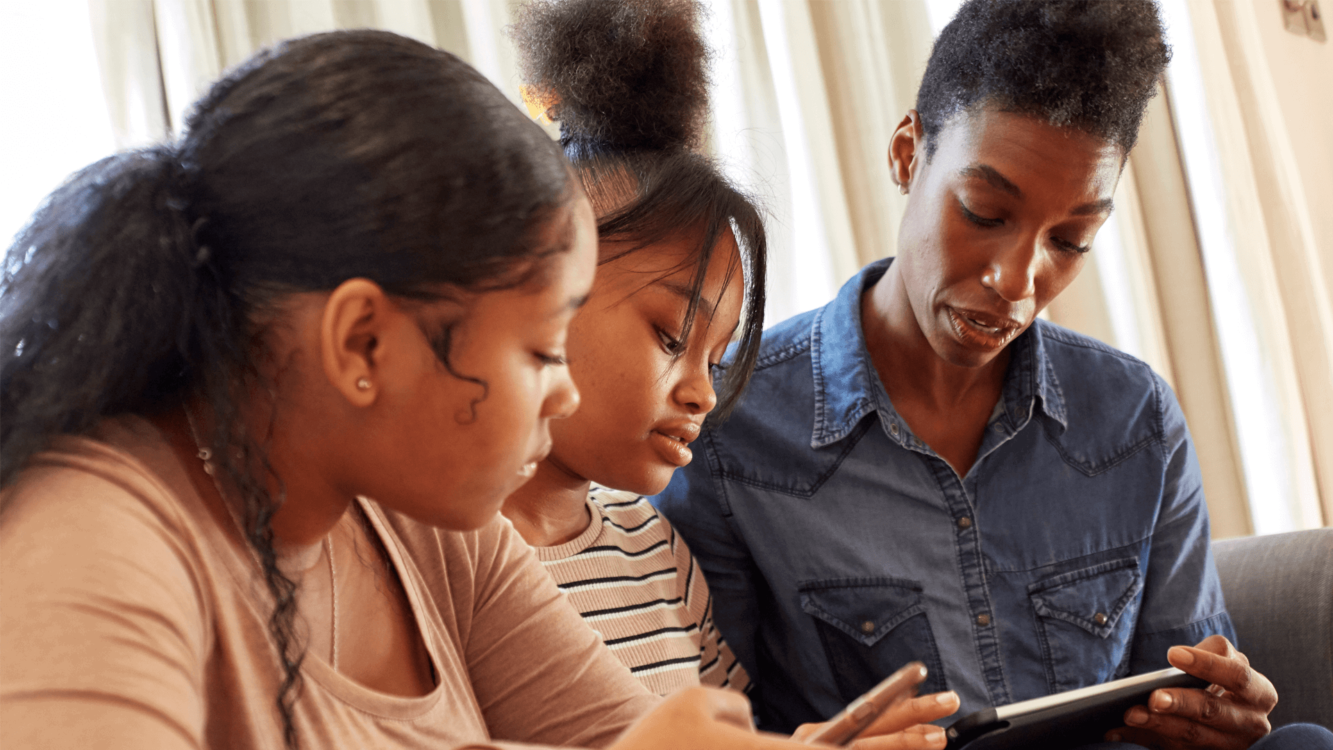 Mother and daughters using mobile devices together 