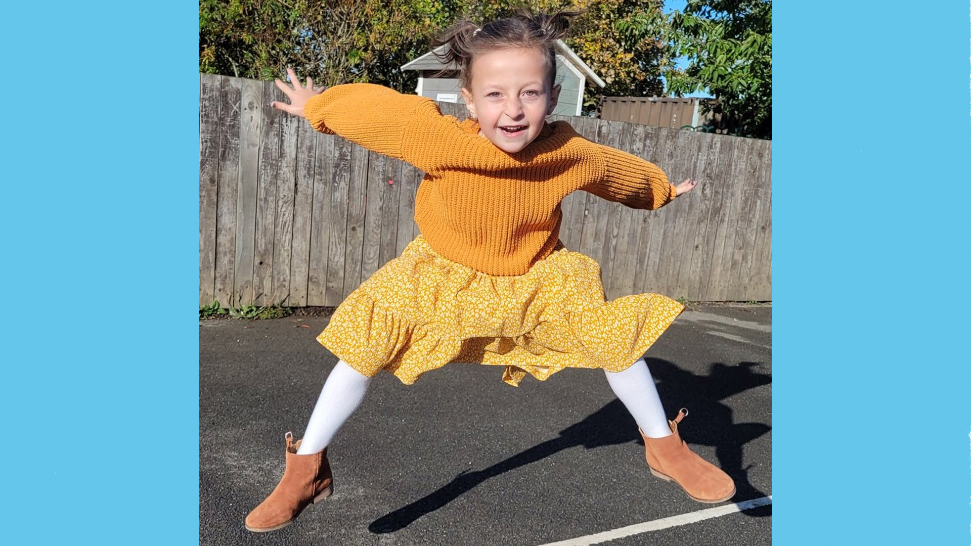 A girl from St Benets Primary School jumps in the playground wearing all yellow.