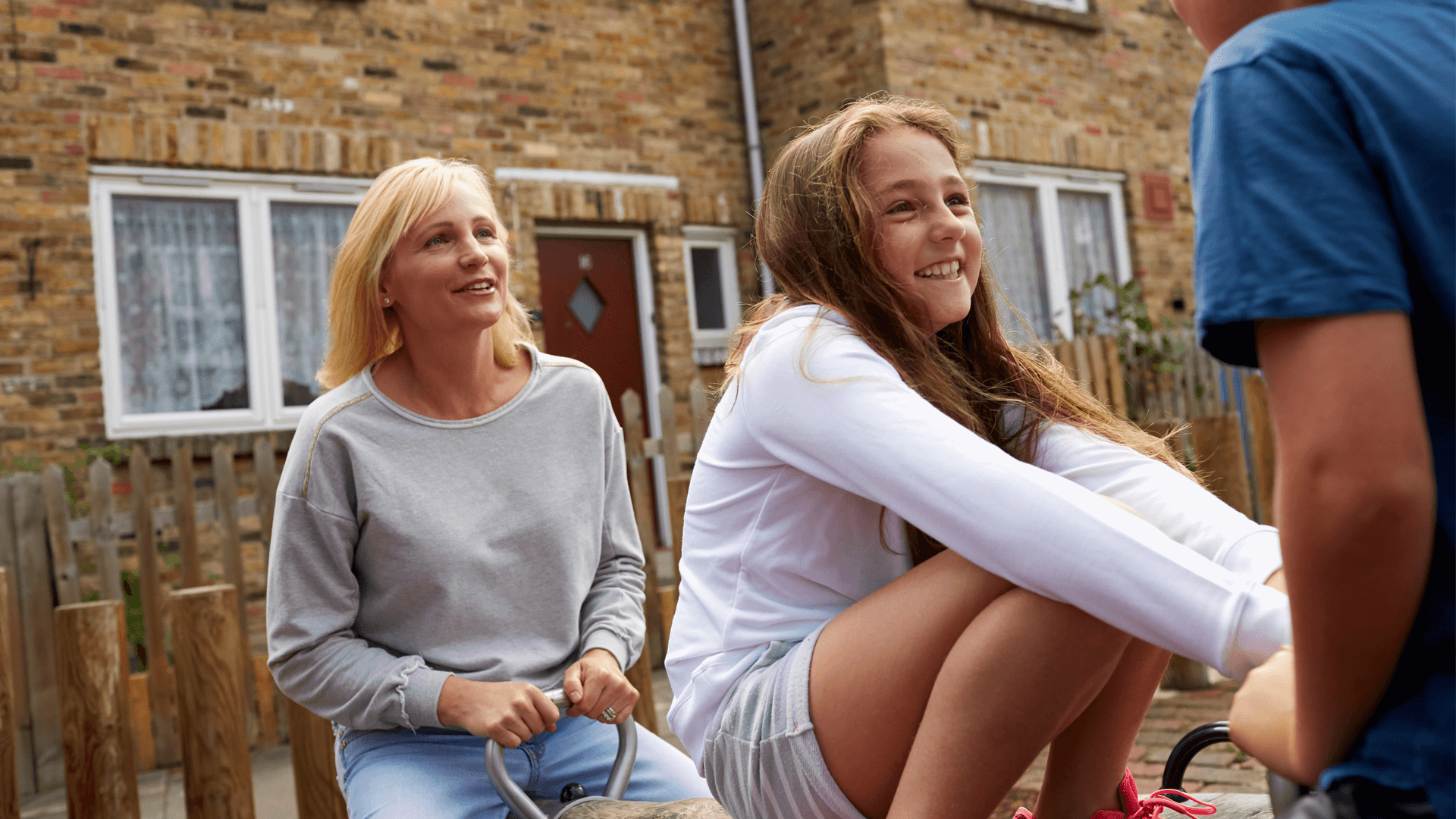 A young girl looking happy with her parents outside their home