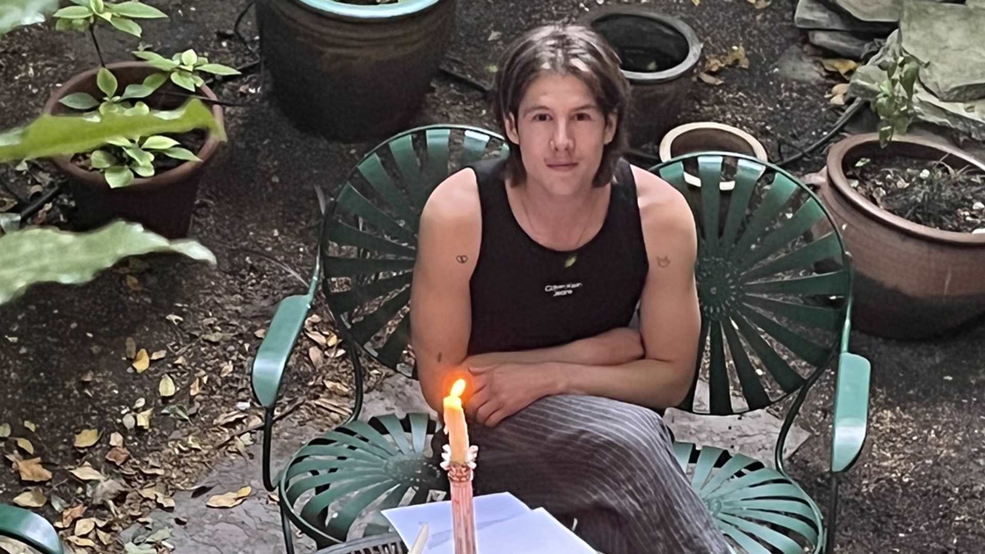 Our fundraiser, Alex D'arbost, sitting at a garden table covered with illustrations for his book.