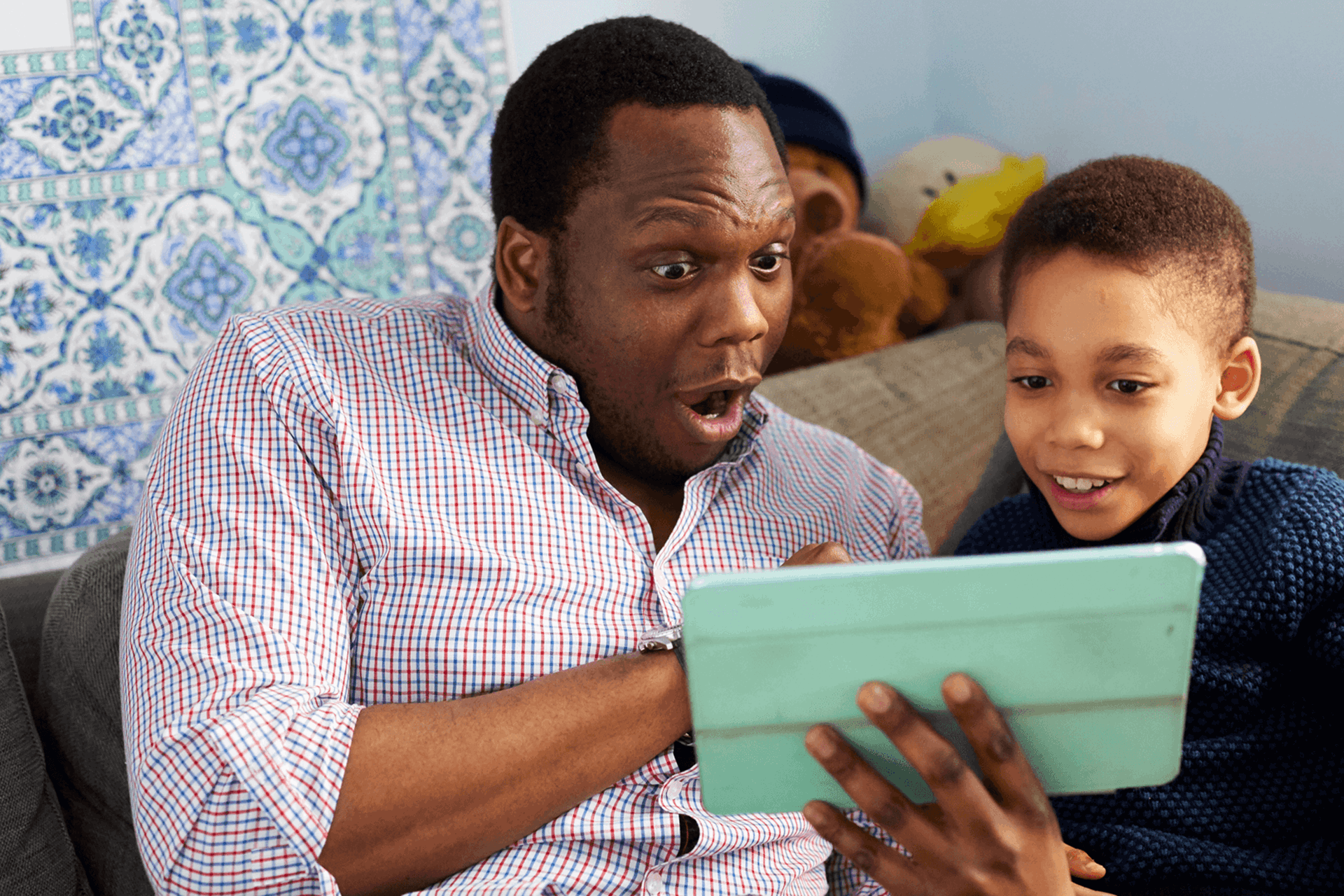 A father and son having lots of fun together on the sofa with a tablet