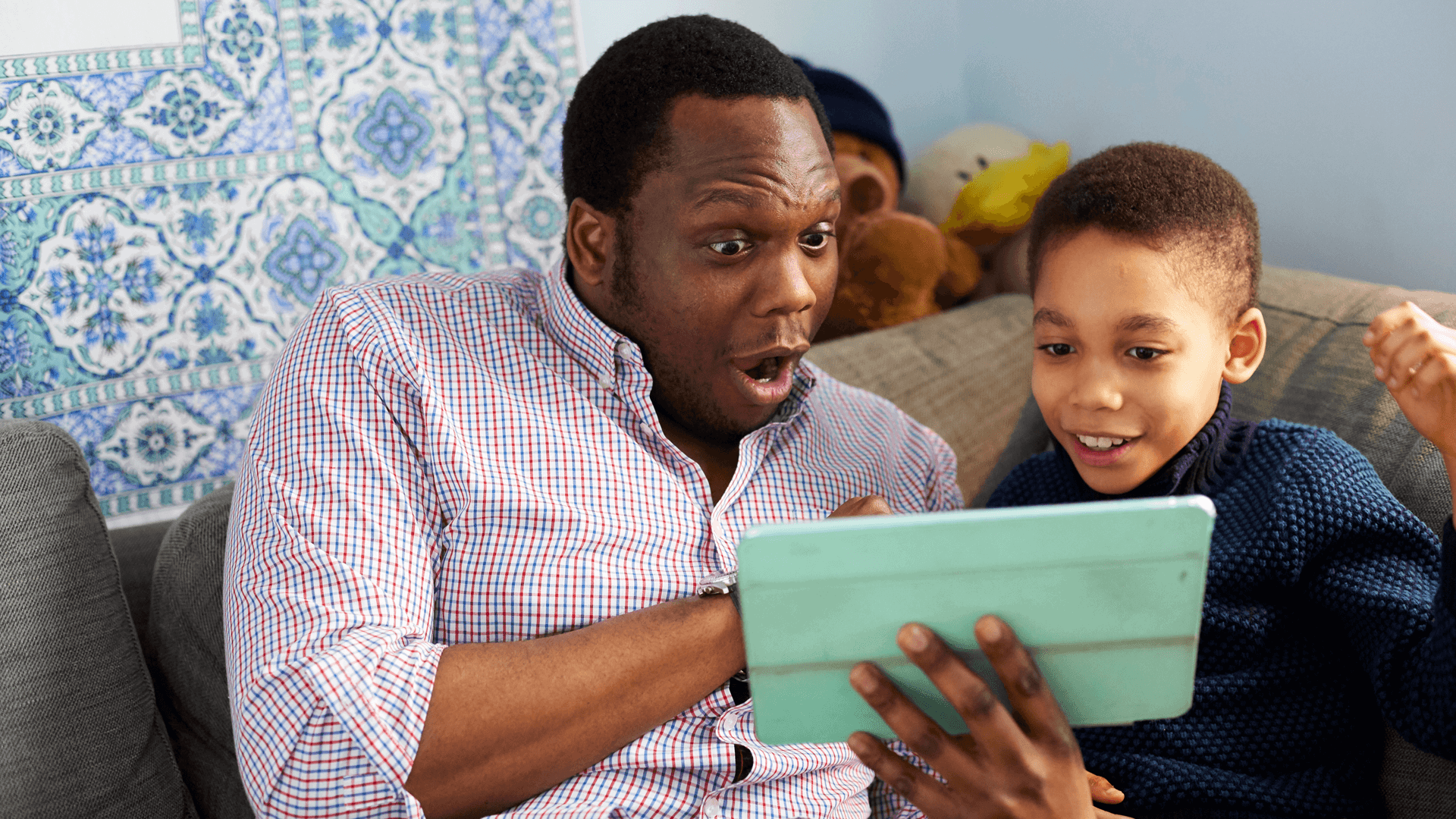 A father and son having lots of fun together on the sofa with a tablet