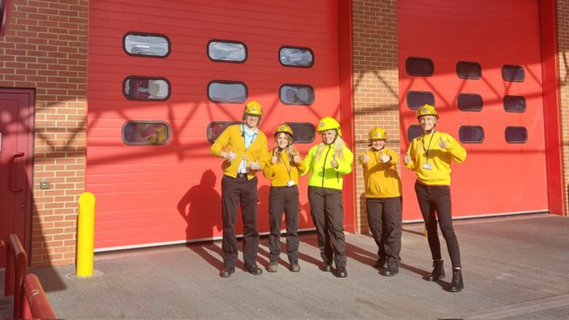 West Yorkshire Fire and Rescue pose in their fire hats wearing yellow.
