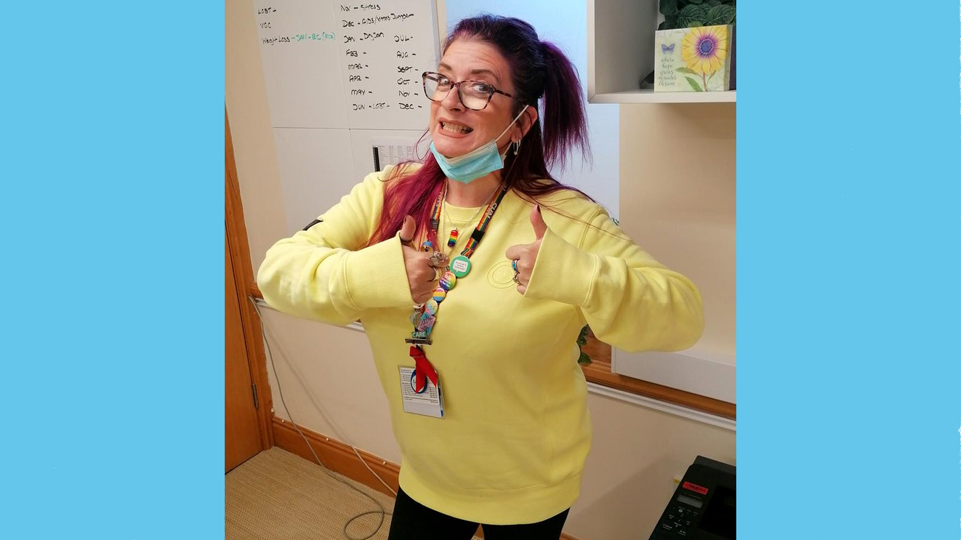 An NHS worker poses in a yellow jumper.