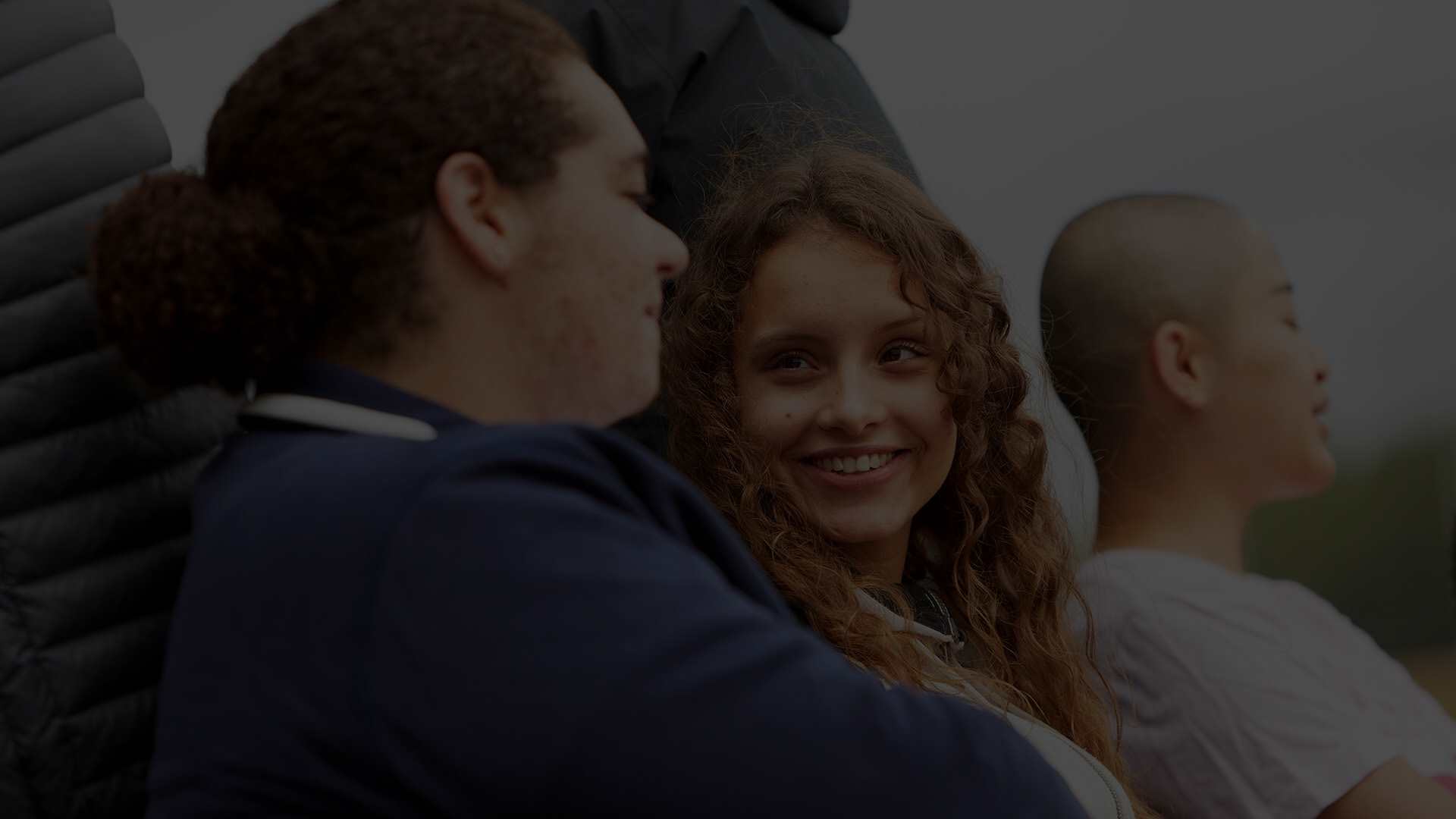 Three young people sat smiling and talking