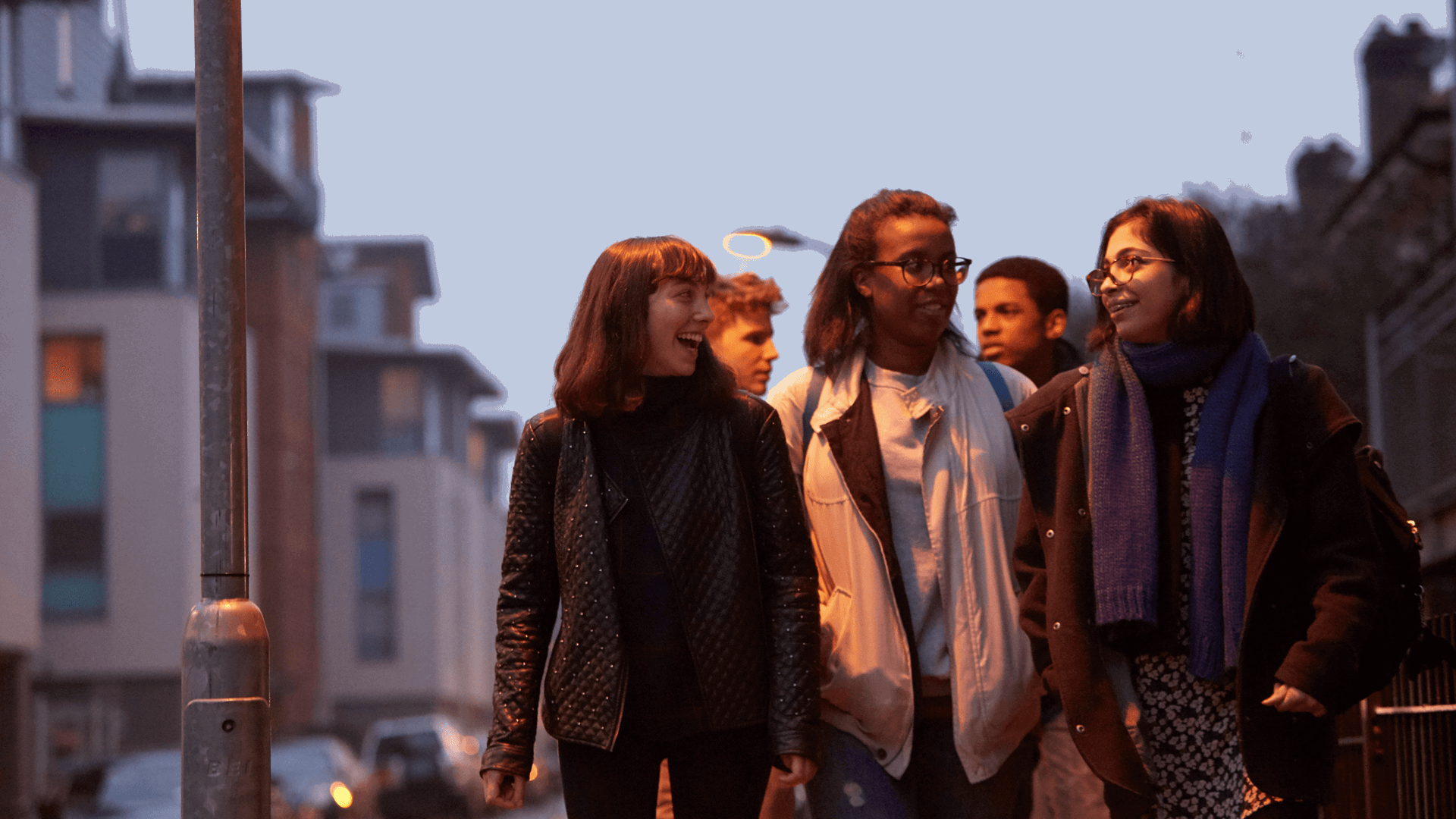 wide-shot-of-a-group-of-young-people-smiling-while-walking-on-a-street-with-houses-at-night