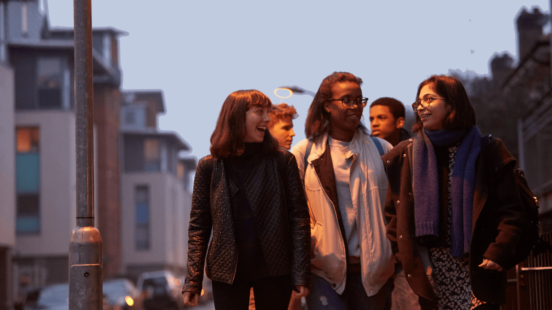 wide-shot-of-a-group-of-young-people-smiling-while-walking-on-a-street-with-houses-at-night