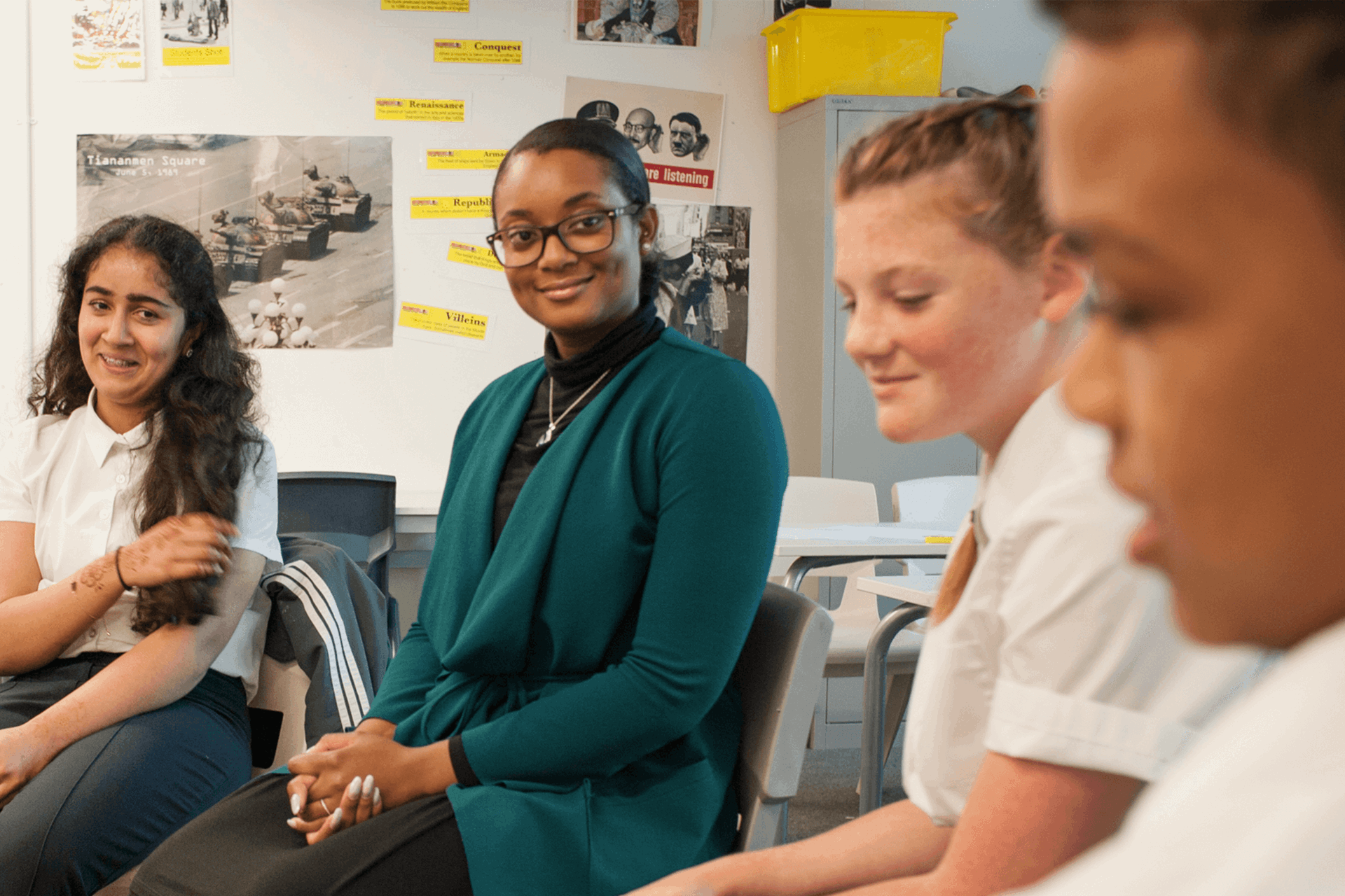 teacher-sitting-with-three-students-in-classroom-smiling