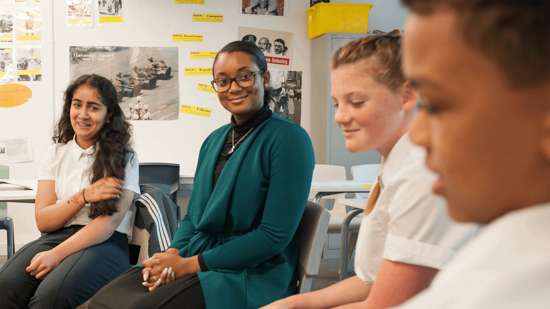 teacher-sitting-with-three-students-in-classroom-smiling