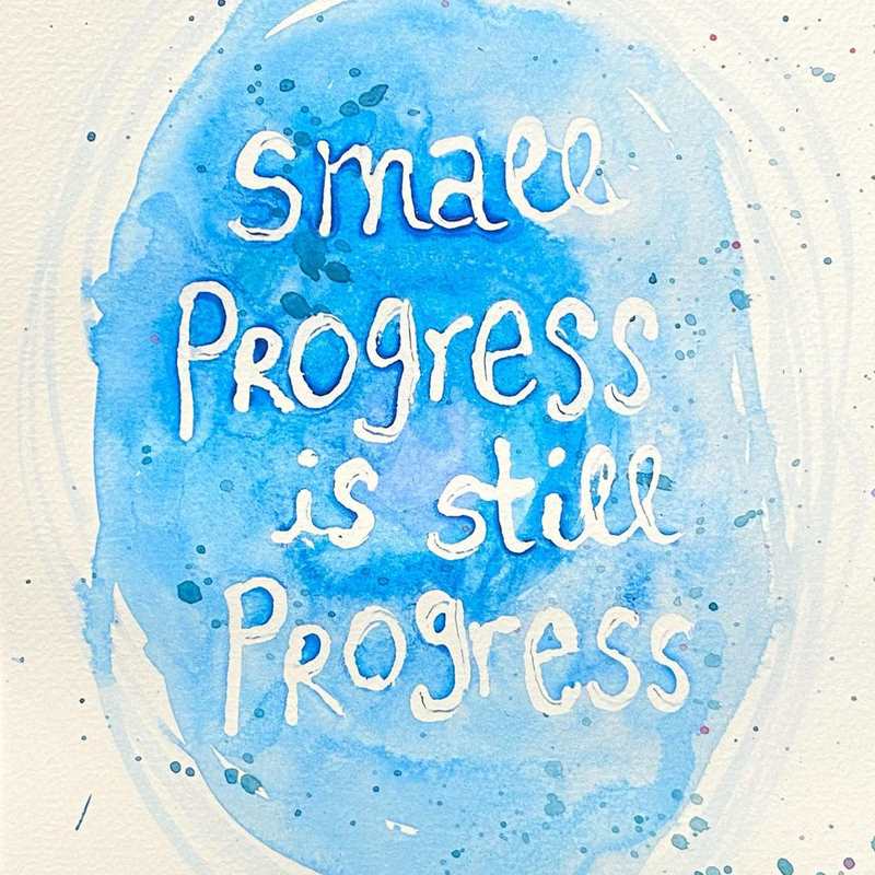 A watercolour image of a blue circle with text in the centre reading: "Small progress is still progress".