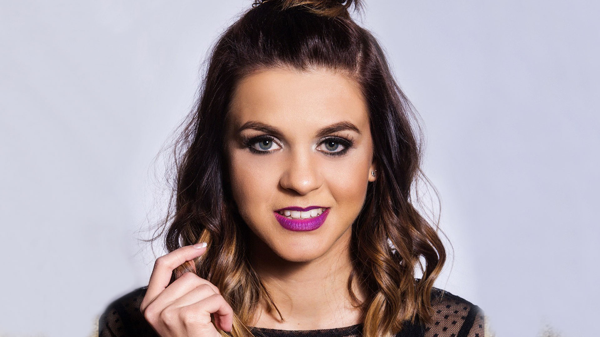 Headshot of Lauren Layfield wearing purple lipstick against a light grey background