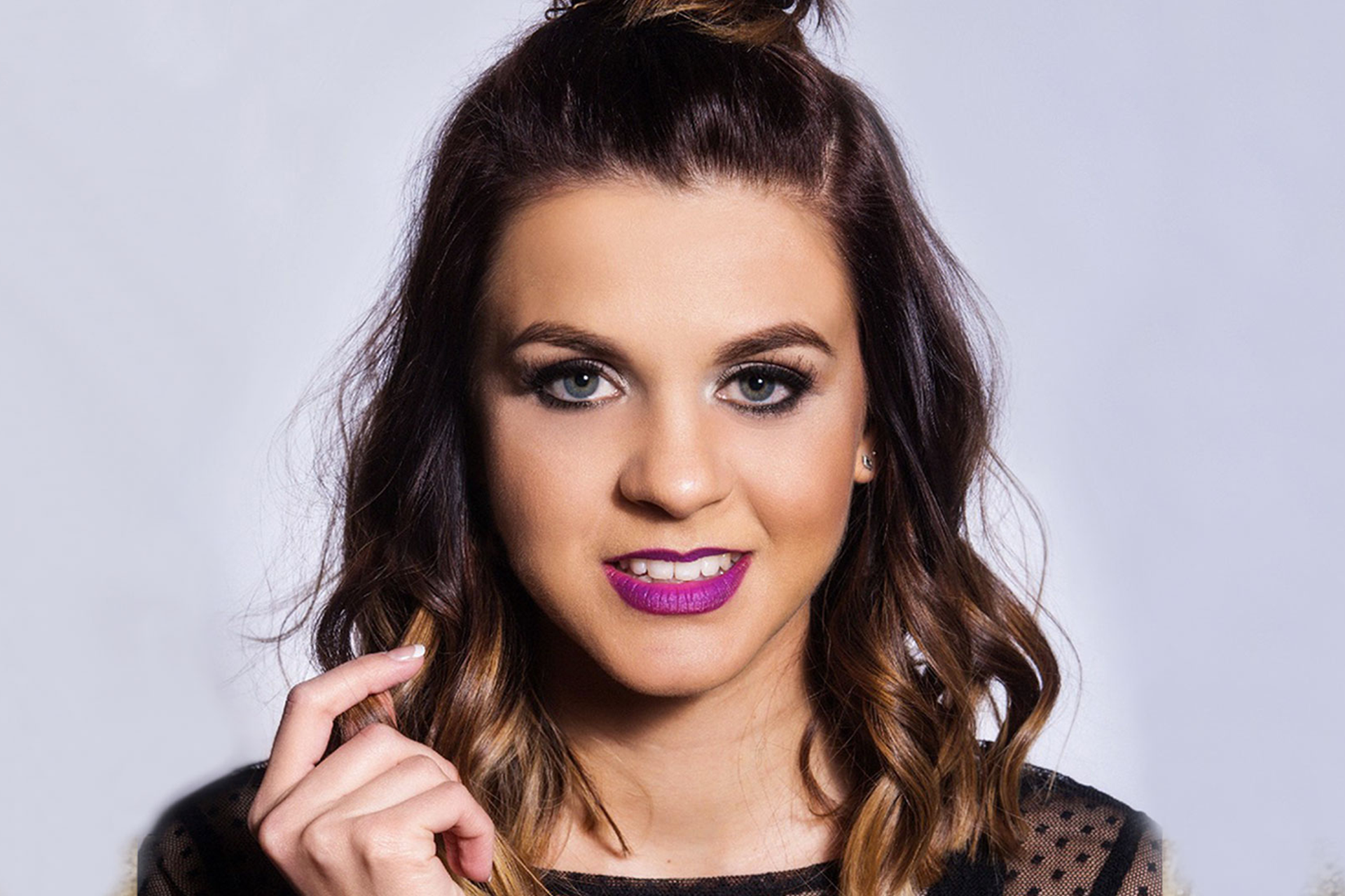 Headshot of Lauren Layfield wearing purple lipstick against a light grey background