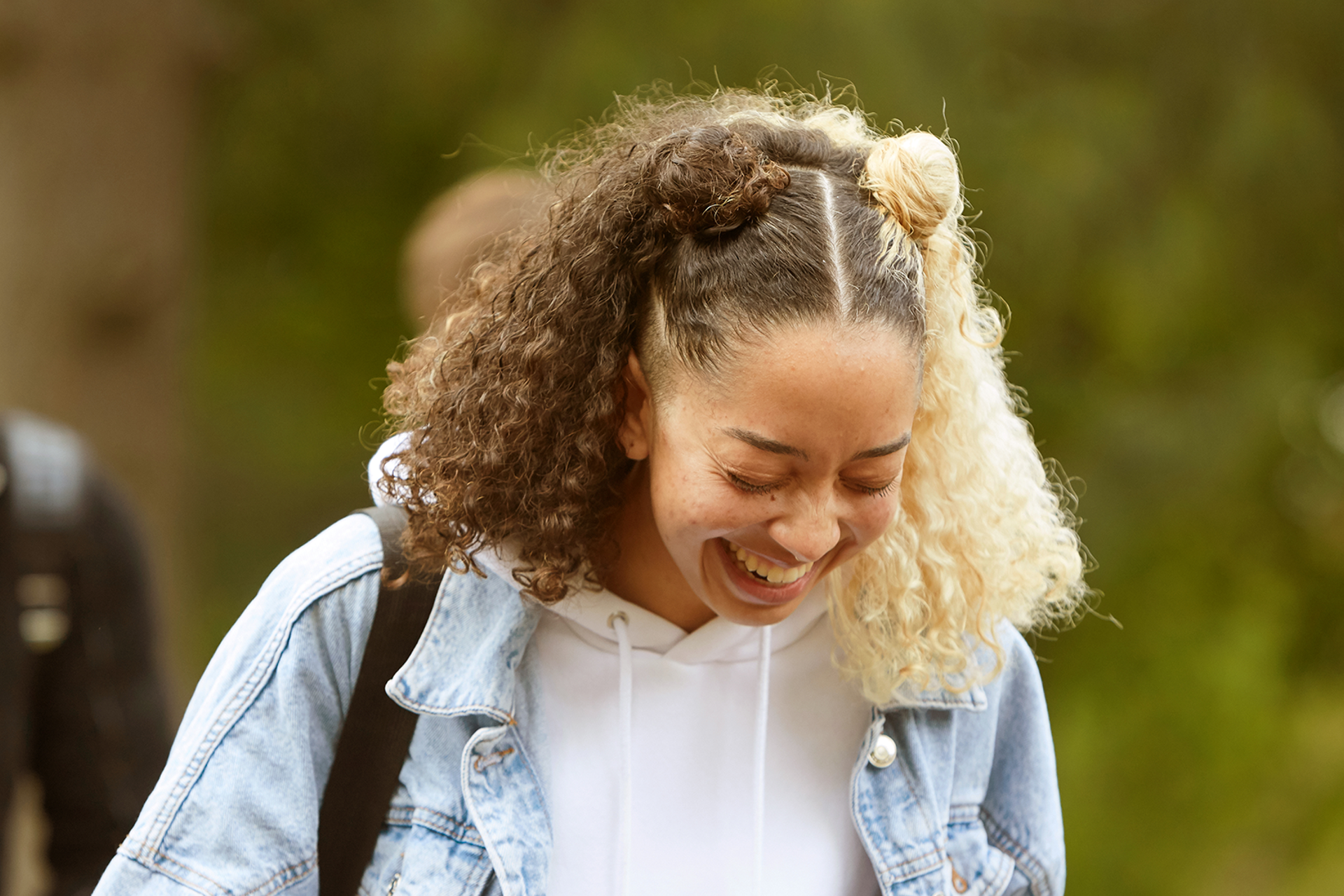 A girl laughing while walking in the park.