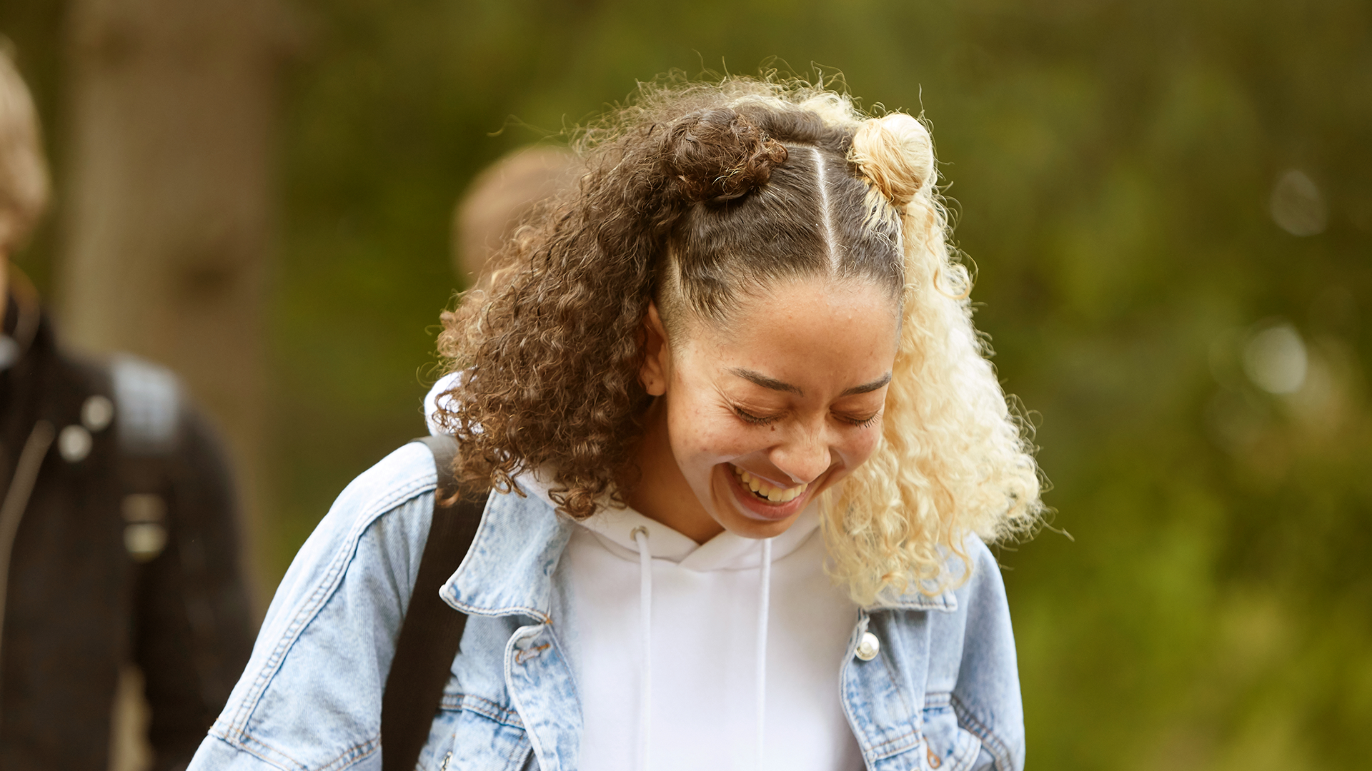 A girl laughing while walking in the park.