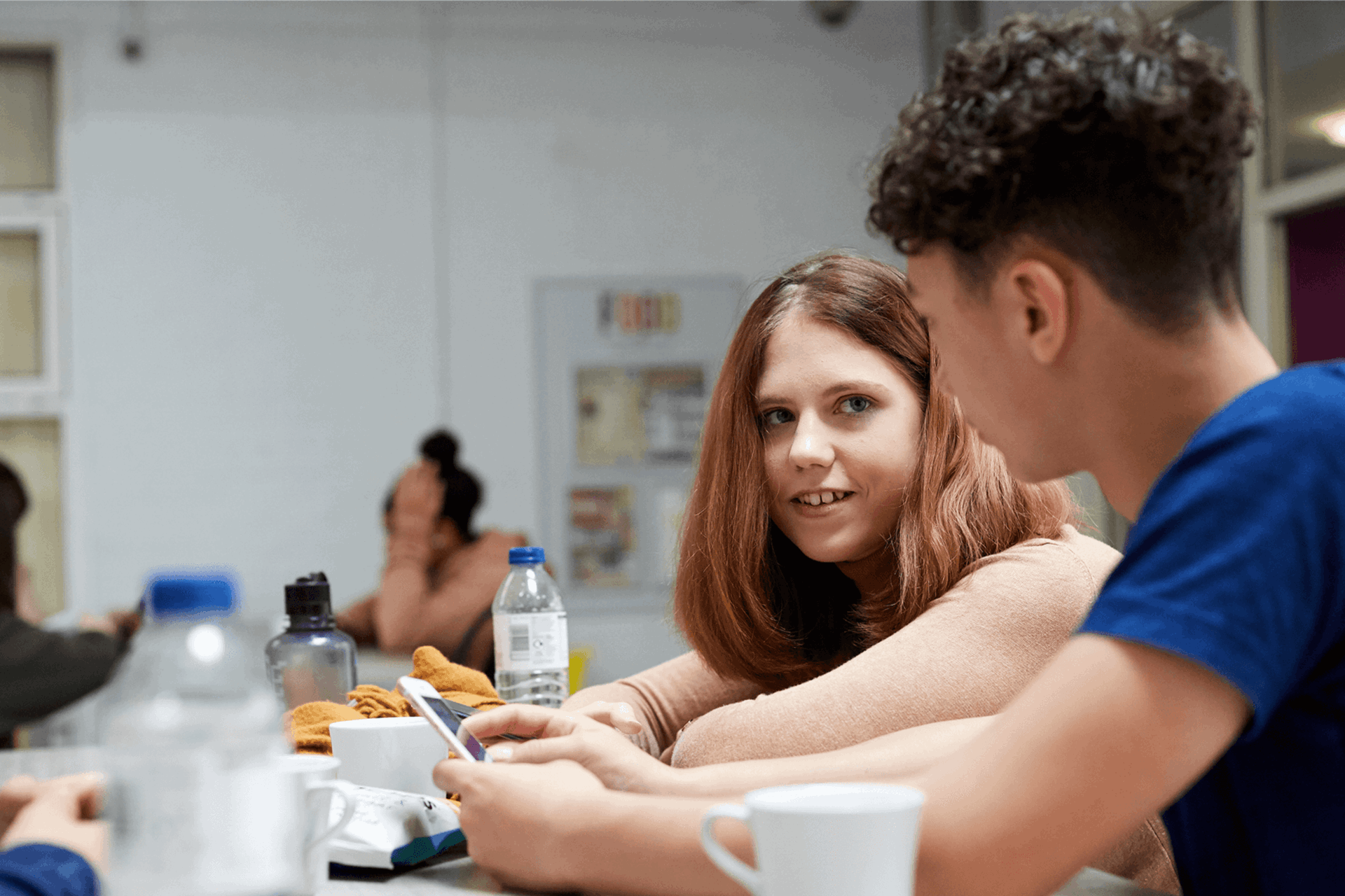 A group of young people sitting together and talking in a school canteen.