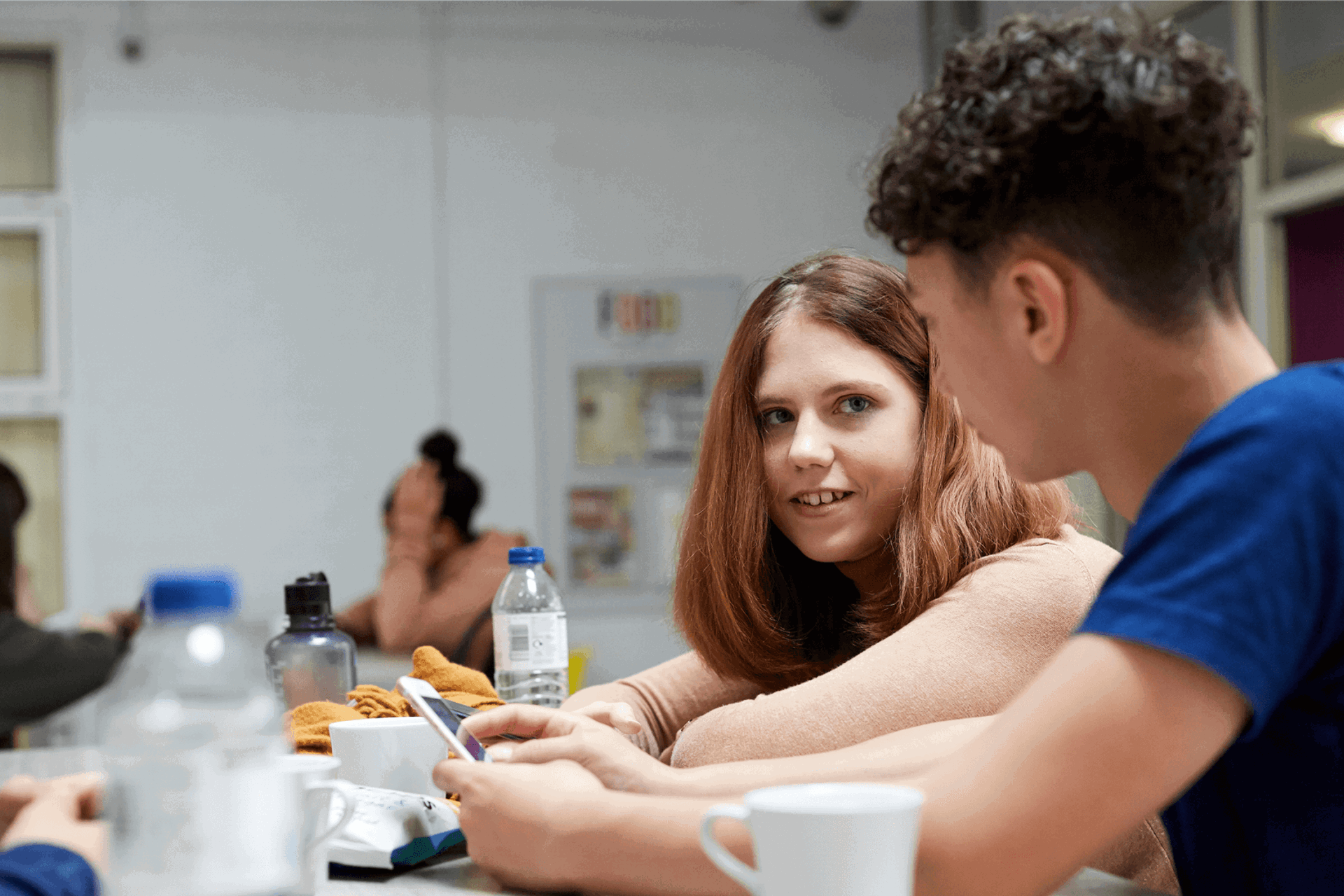 A group of young people sitting together and talking in a school canteen.
