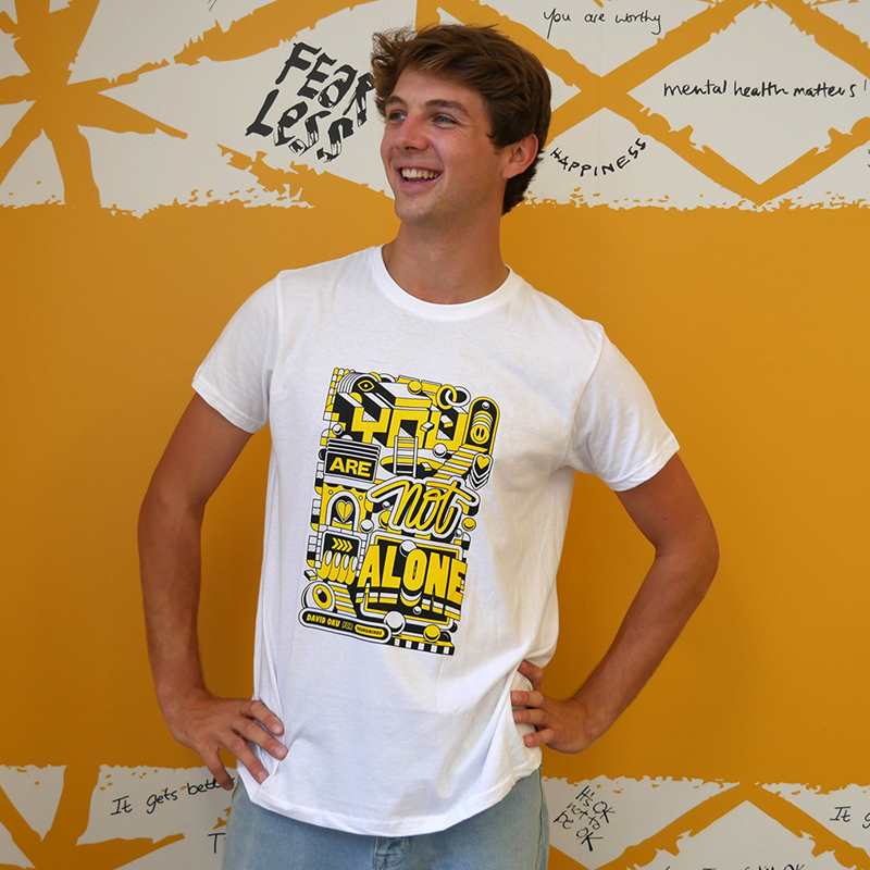 A man smiling wearing  our David Oku's bespoke 'You are not alone' graphic #HelloYellow T-shirt.
