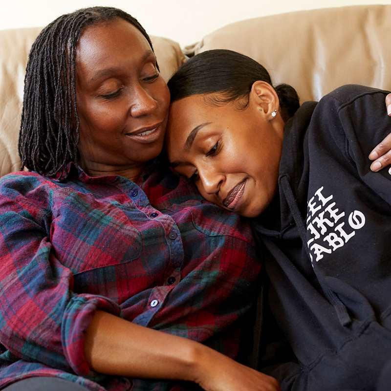 A mother hugging her daughter on the sofa