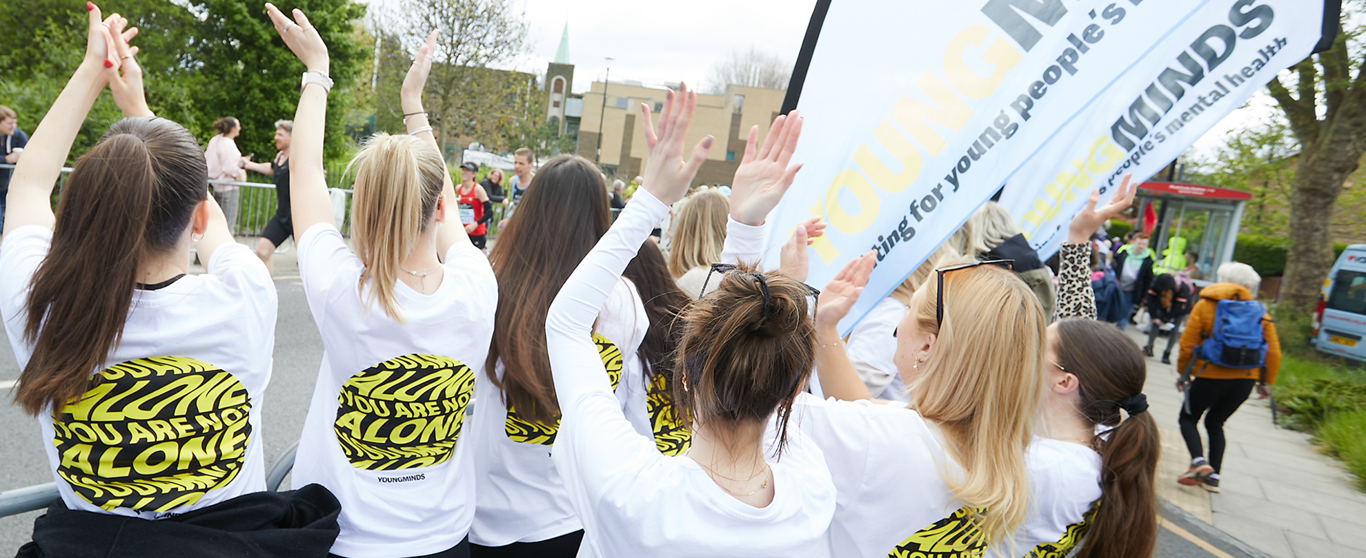 YoungMinds staff cheering marathon runners on from the side line in YoungMinds t-shirts and with YoungMinds banners.