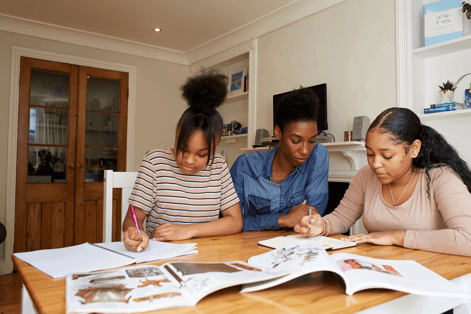 A mother and two daughters working together at a table doing homework