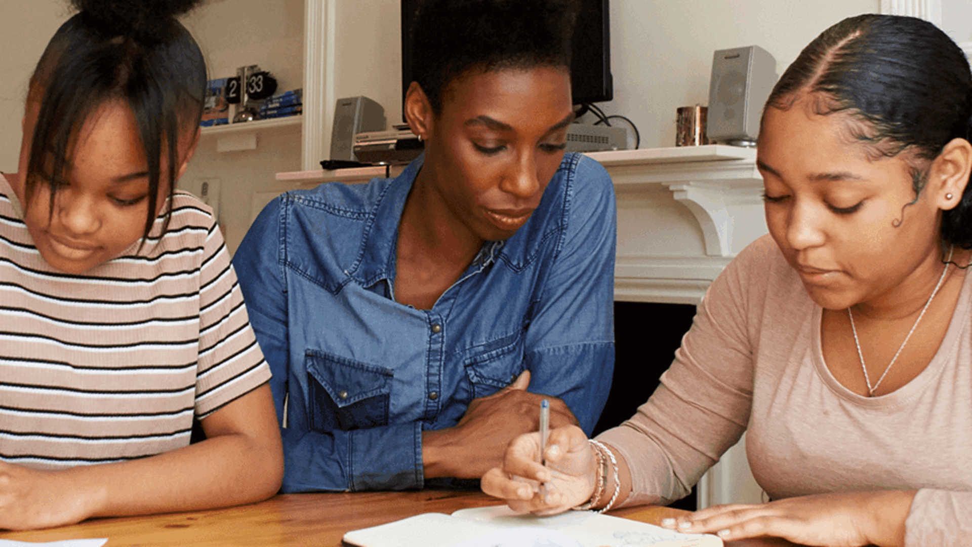 A mother and two daughters working together at a table doing homework