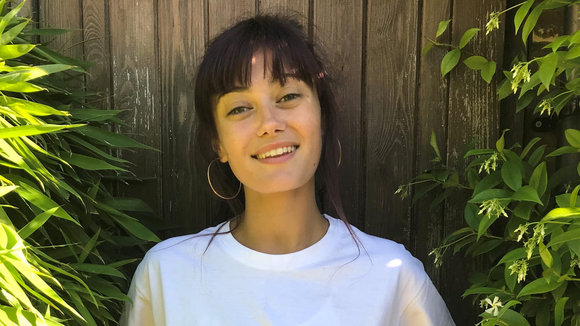 Ella Purnell smiling and wearing a white T-shirt in the garden