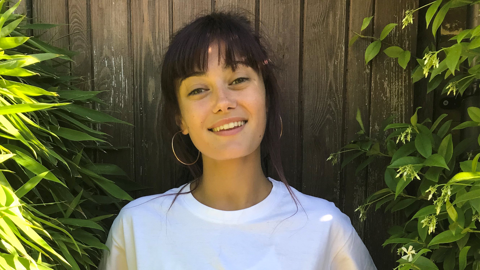 Ella Purnell smiling and wearing a white T-shirt in the garden.