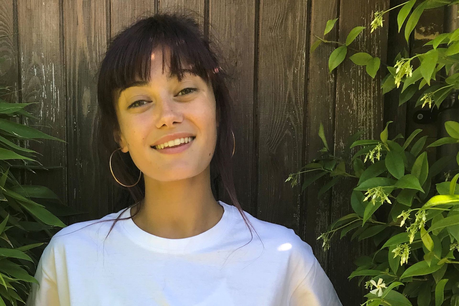 Ella Purnell smiling and wearing a white T-shirt in the garden.